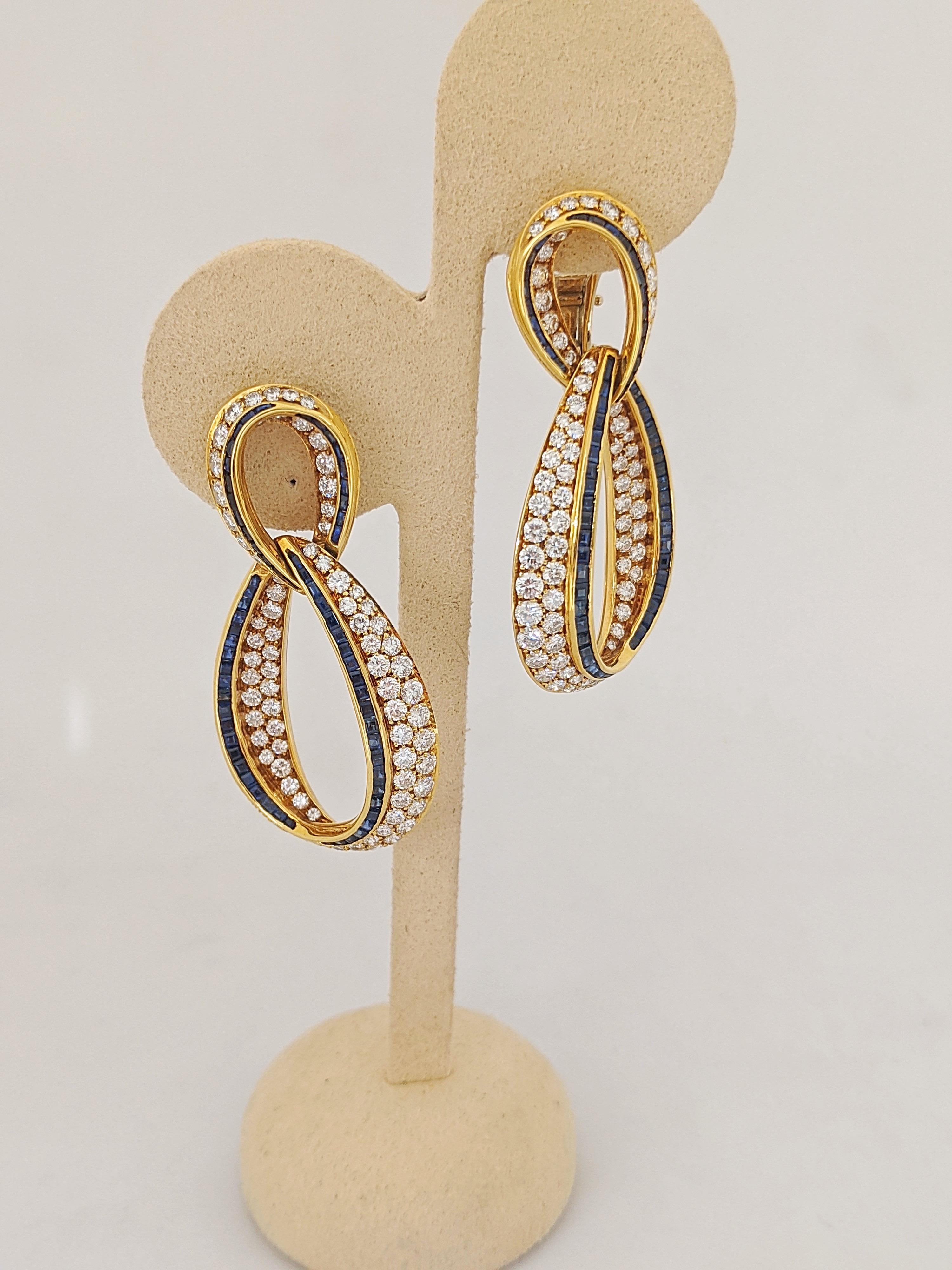 A lovely pair of 18 karat yellow gold earrings set with round brilliant cut Diamonds and Blue Sapphires. The earrings are formed with two interlocking teardrop shapes. The pave setting of the stones is done so beautifully , highlighting the inside