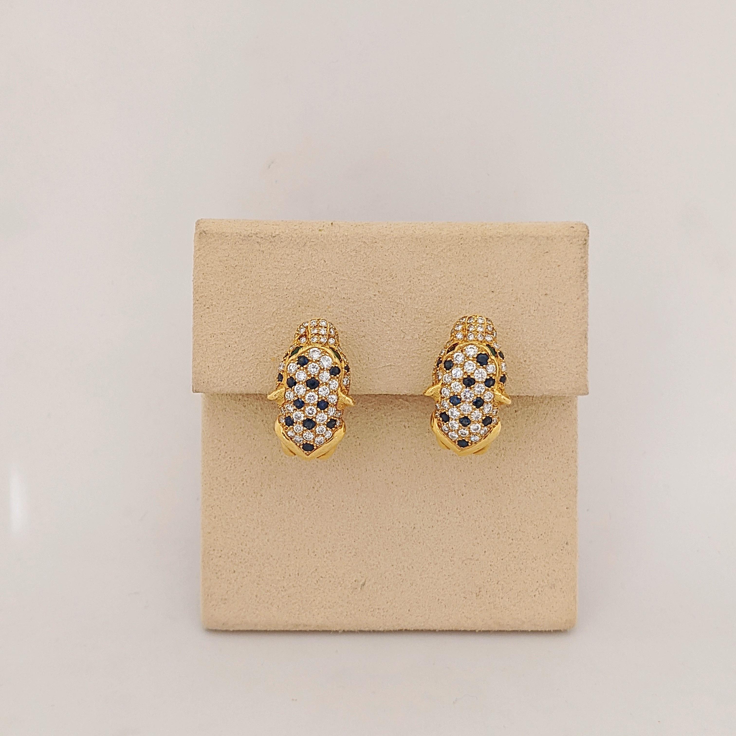 18 Karat Gelbgold Pantherkopf-Ohrringe . Die Ohrringe sind mit eingefassten Diamanten und blauen Saphiren besetzt. Die Augen des Panthers sind marquisförmige Smaragde. Die Ohrringe messen 1