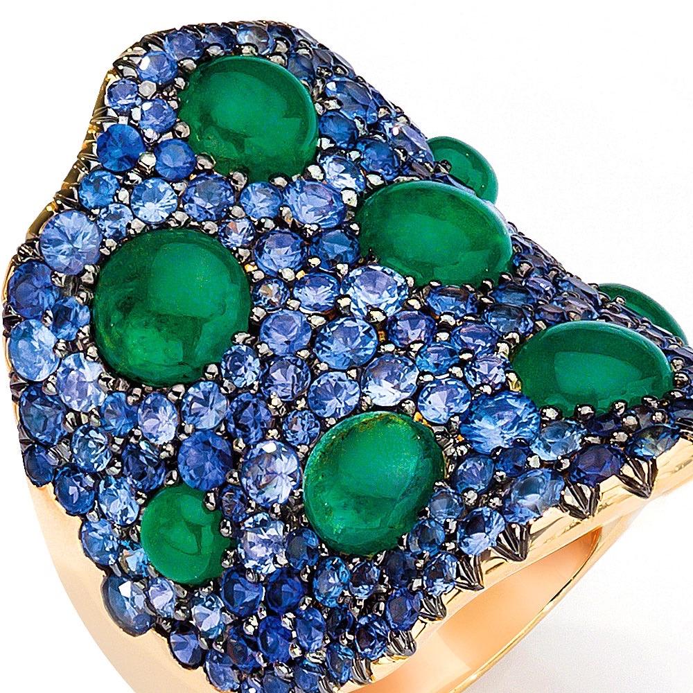 This 18 karat yellow gold wide wave ring is pave set with blue sapphires. Cabochon emeralds are set against the blue sapphires for a dramatic contrast. The ring measures approximately 1