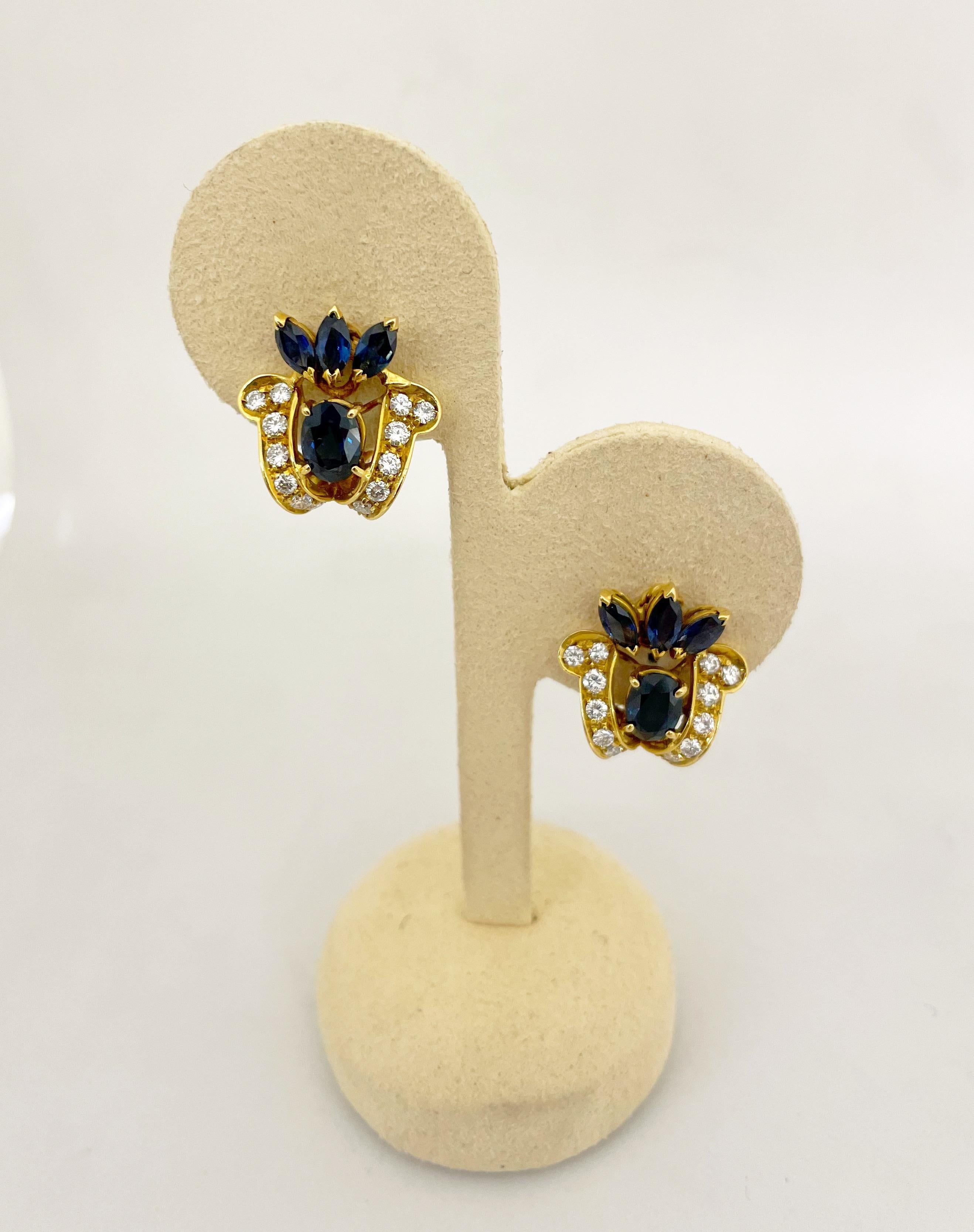 18 karat yellow gold earrings beautifully designed with 6 marquis and 2 oval blue sapphires. A total of 28 round brilliant diamonds highlight the blue sapphires . These earrings measure 7/8