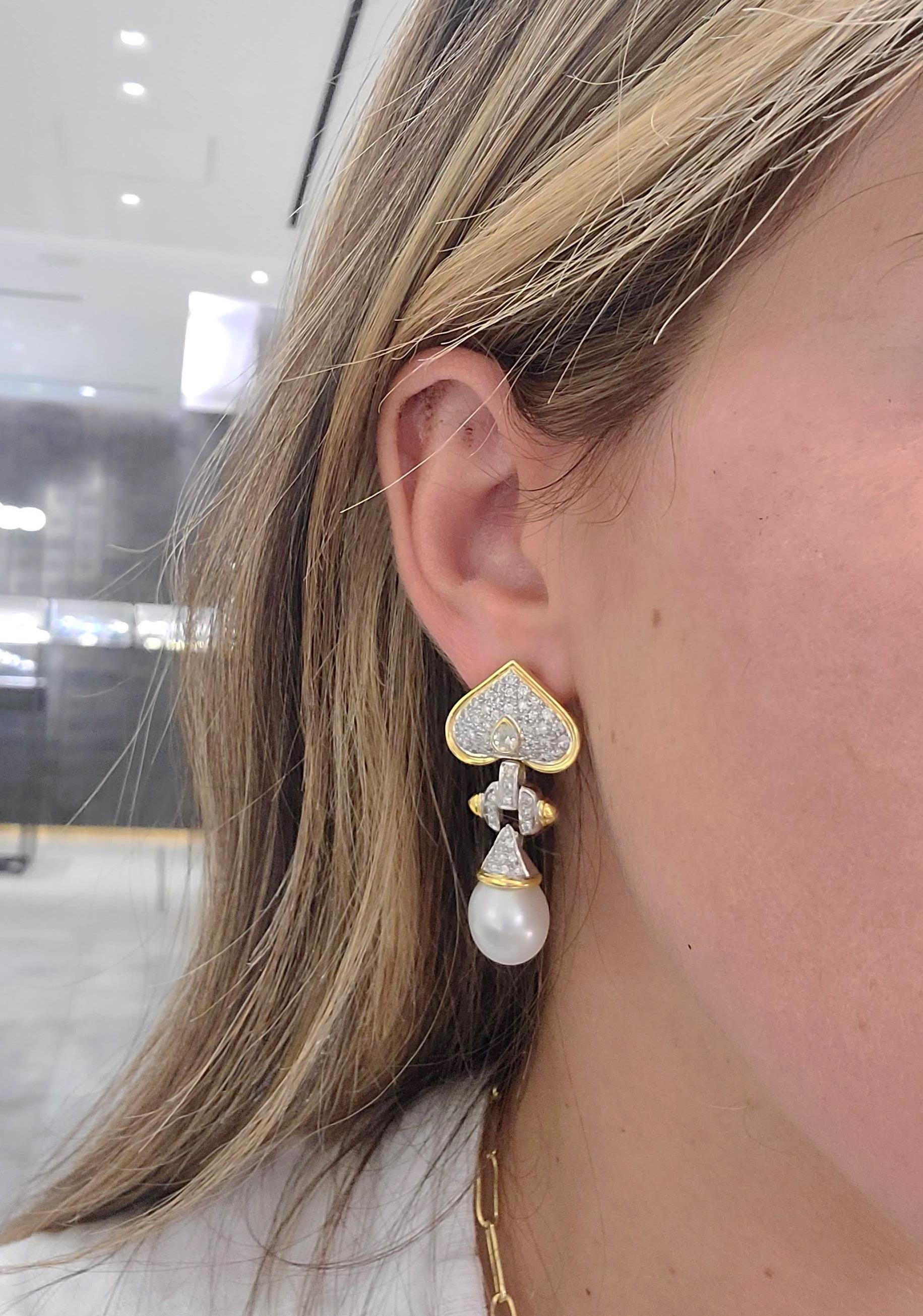 These earrings are designed with 18 karat yellow gold heart shapes that have been pave set with Diamonds. A single pear shaped bezel set Diamond is in the center of each heart. A detachable Diamond capped South Sea Pearl drop hangs from the gold and