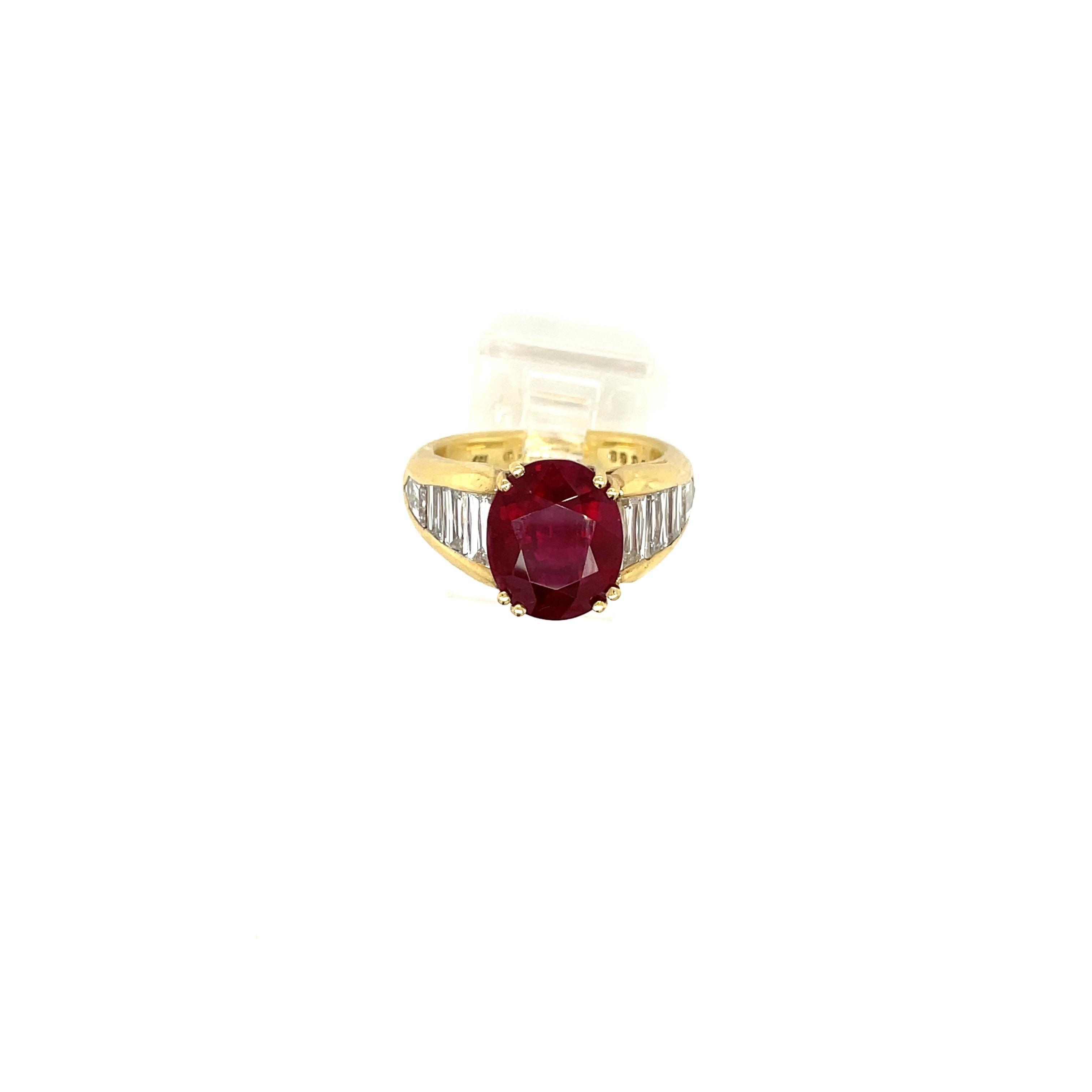 This 18 karat yellow gold ring centers a magnificent oval ruby weighing 5.96 carats. The setting is designed with 3 baguettes diamonds on each side, along with a bullet shaped diamond at its bottom. This setting highlights the center beautifully