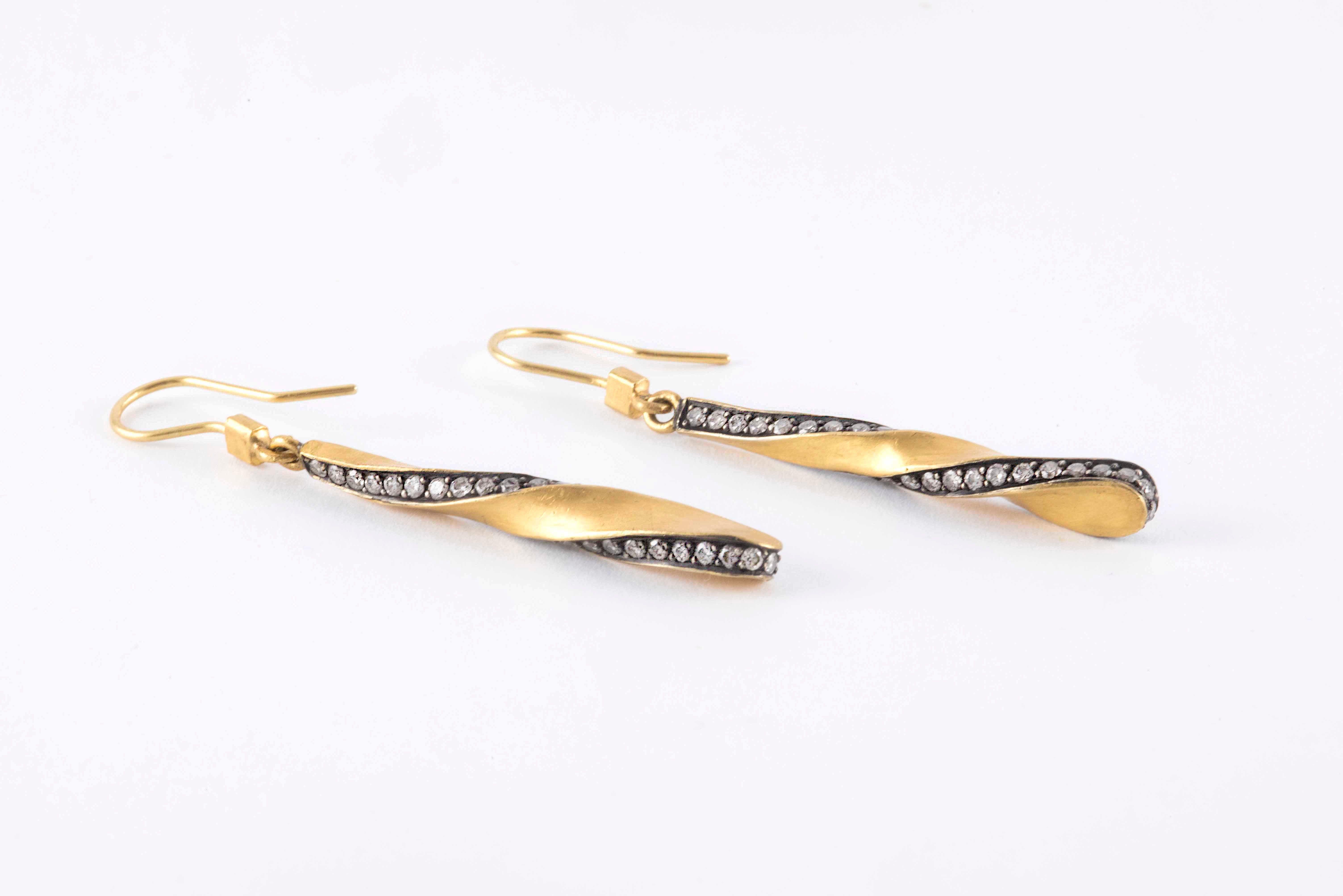 These dangle earrings handcrafted in 18kt yellow gold and darkened gold in a spiral design feature eighty-four round diamonds totaling approximately 1.20 carats. The earrings measure about two inches long. 

