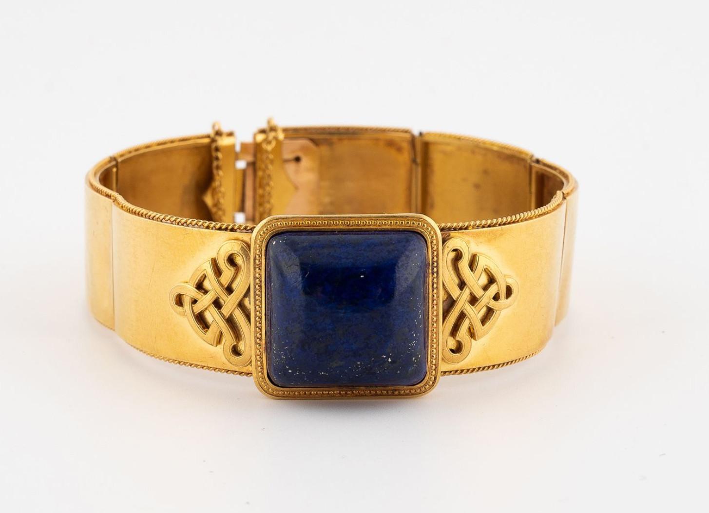 Articulated ribbon bracelet in 18kt yellow gold centered with a large cabochon of lapis lazuli supported by two chiseled applied scrolls.
Diameter 6 cm
Circa 1870's
Gross weight: 35.5g.