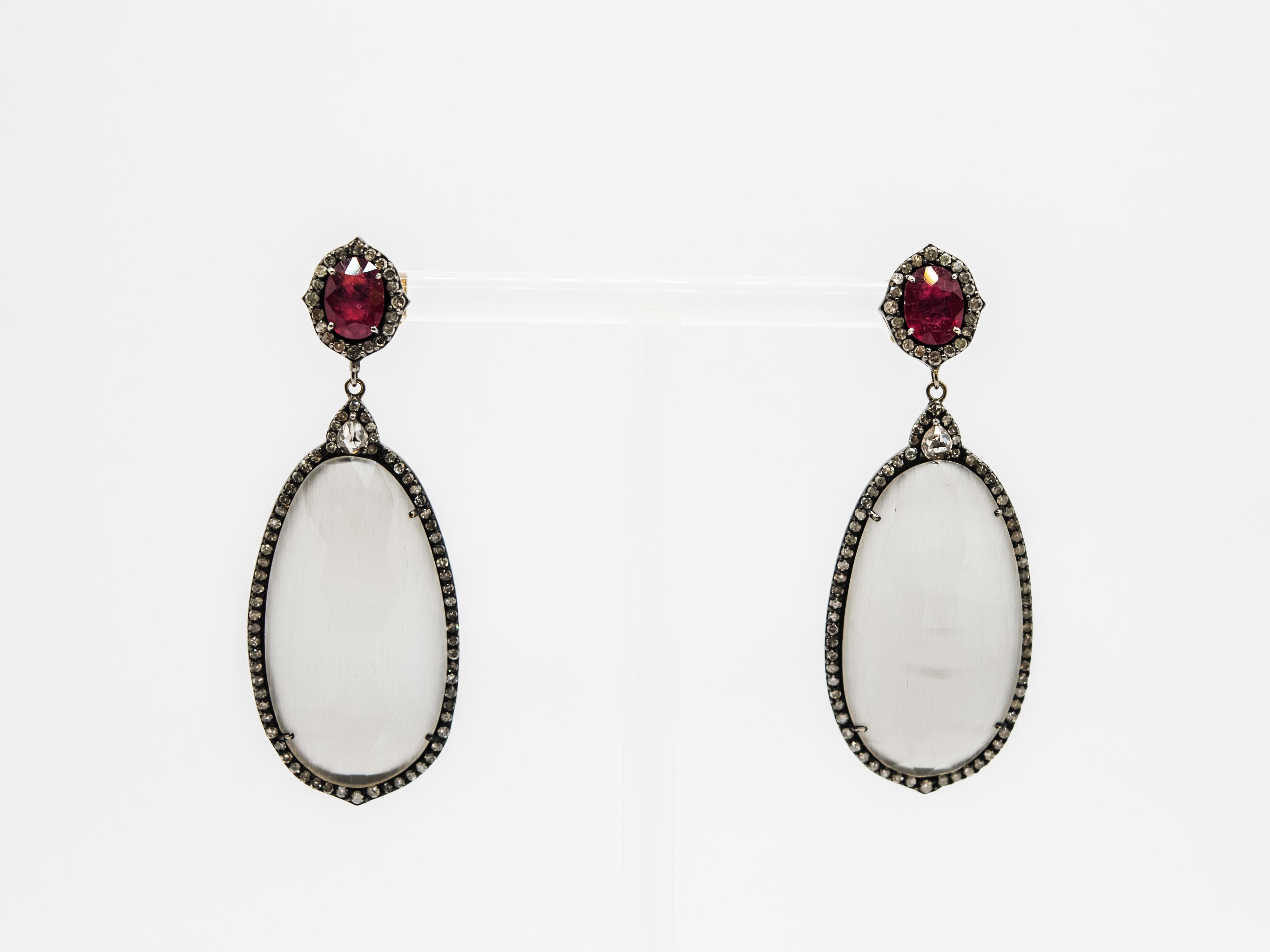 These elegant retro inspired dangle earrings have a burnished silver frame and 18kt yellow gold closure.
Both faceted grey Agate and oval cut Rubies are surrounded by icy gray Diamonds.
A drop cut brown Diamond enhances the center of this beautiful