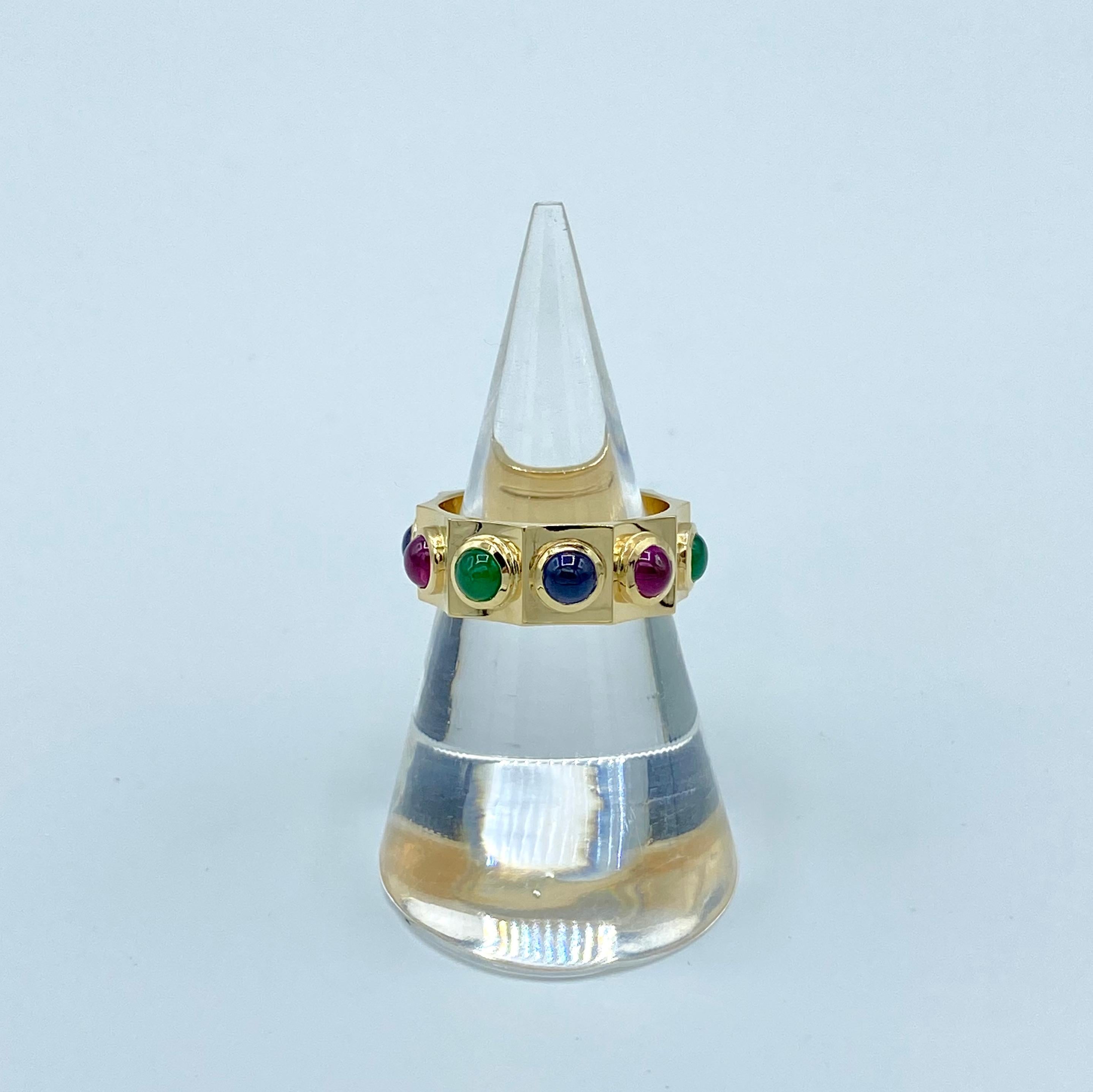 This band ring is divided along its surface into ten concave parts. It comes from the study of medieval goldsmiths and is enriched with cabochons of emeralds, sapphires and rubies that are different from each other. The stones with a diameter of 4