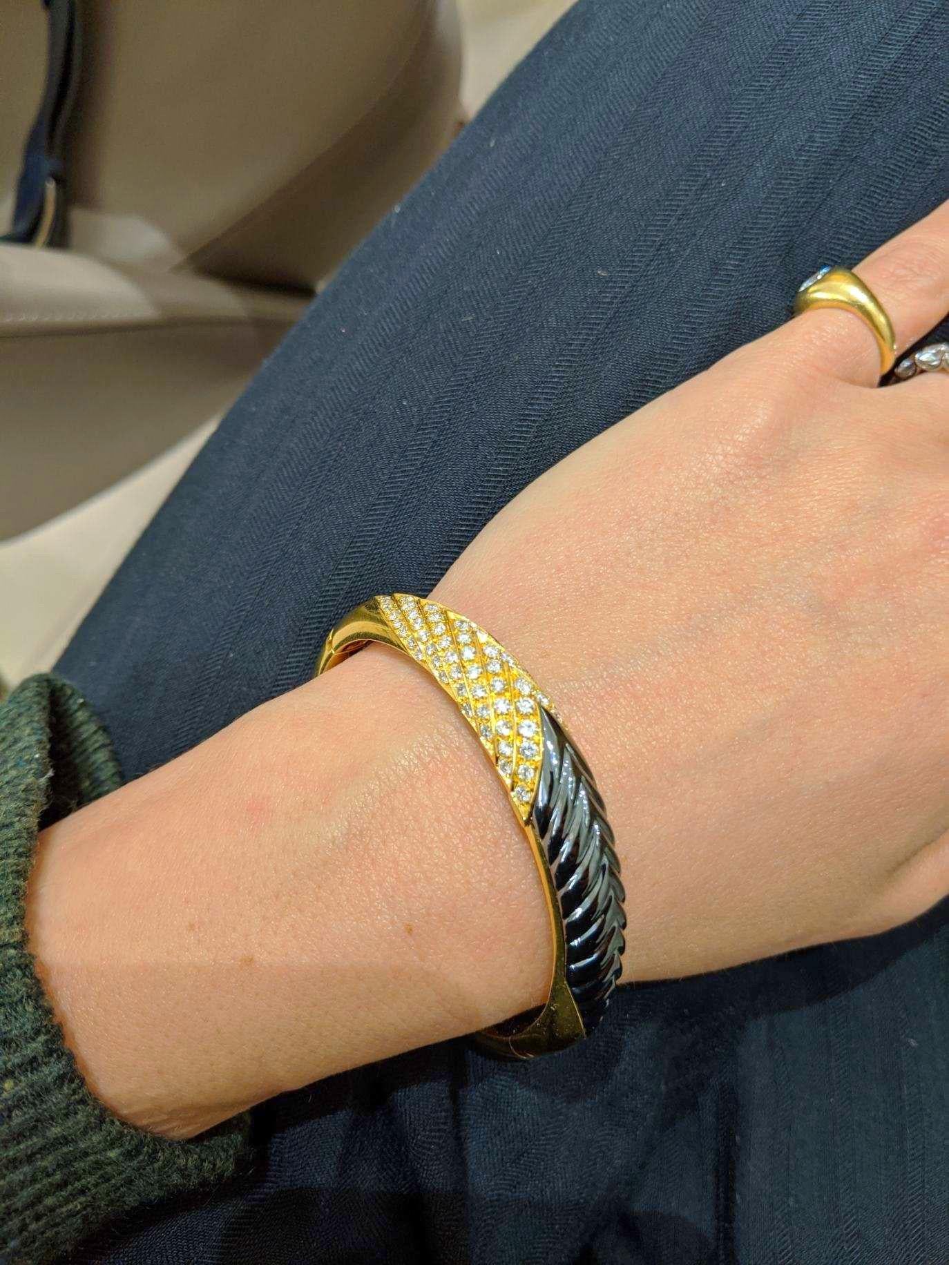 A beautiful 18 karat yellow gold bangle bracelet . Half of  the bracelet is set with round brilliant Diamonds, the other half with hand carved Hematite. The Hematite is fluted and the Diamond setting follows the same pattern....A beautiful contrast