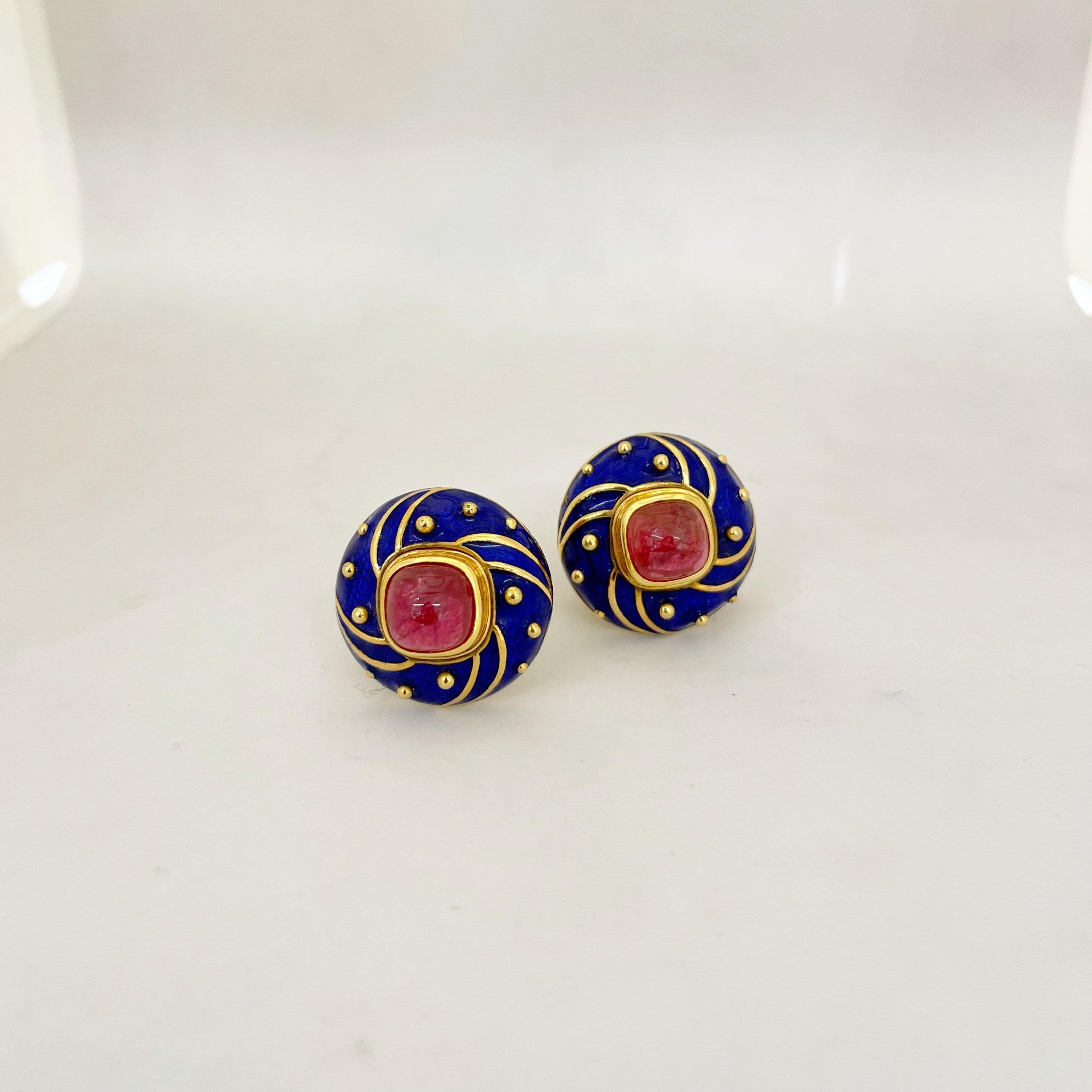 Cellini NYC 18 karat yellow gold button style earrings. These classic earrings are designed with a brilliant blue enamel accented with yellow gold beads and swirls. The earrings center bezel set cabochon pink tourmalines. The earrings are pierced