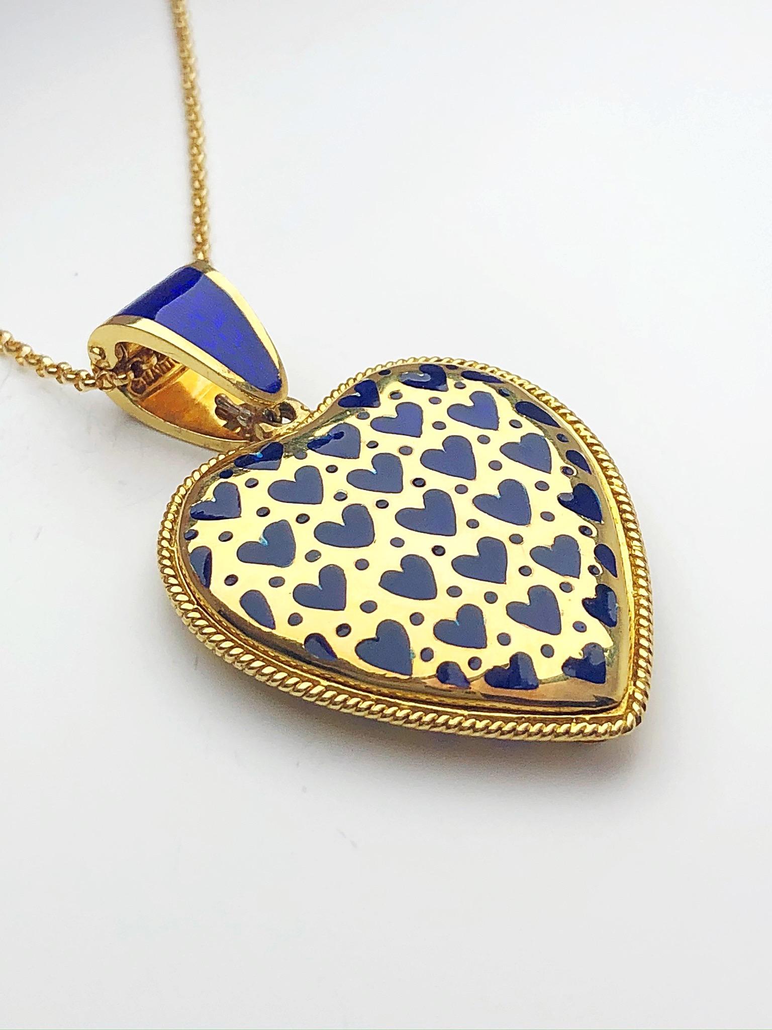 This beautiful heart shaped pendant is crafted in 18 karat yellow gold. Small blue enamel heart shapes make the pattern on the front of the heart. The back of the heart pendant is beautifully finished with an array of heart cutouts. The pendant has