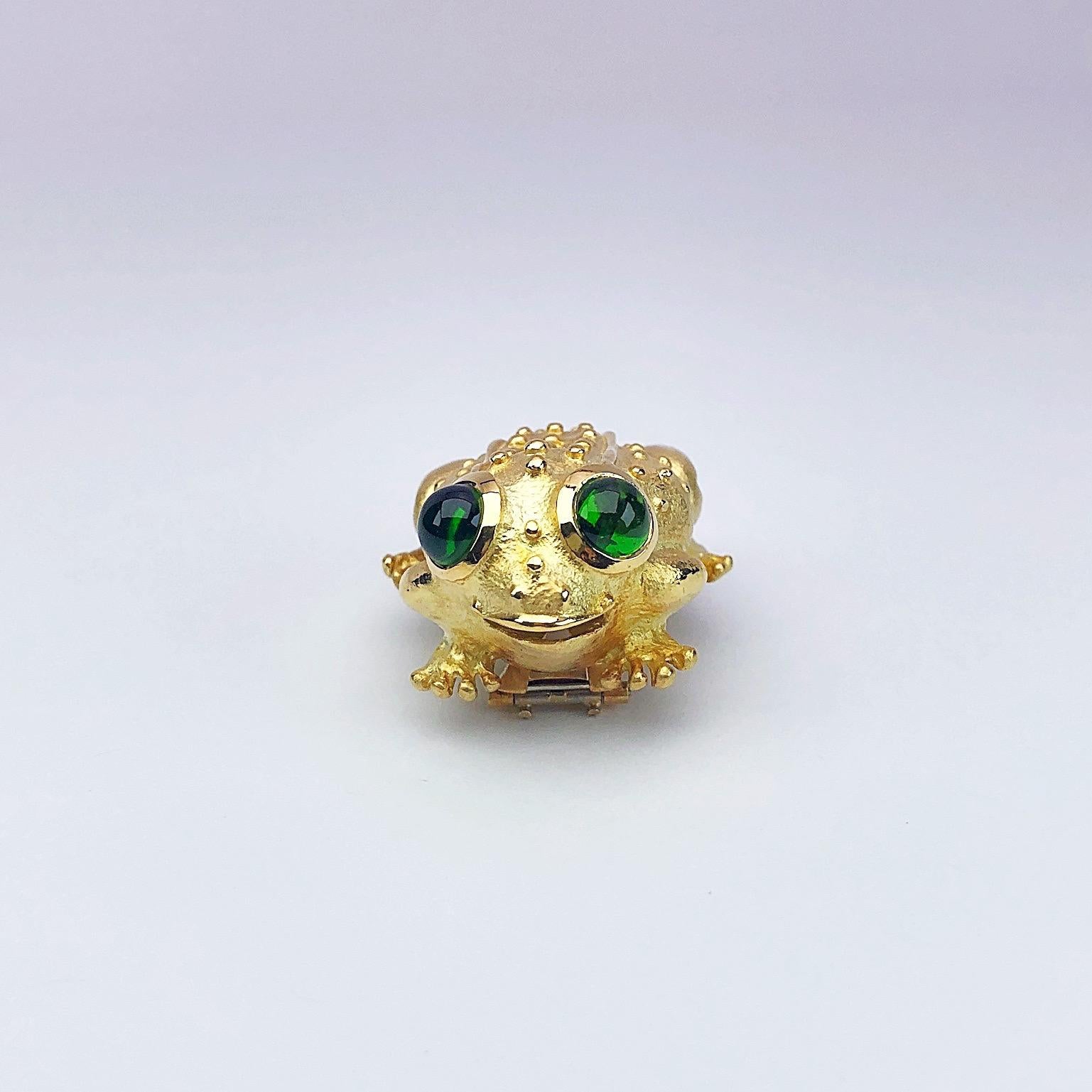 18 karat yellow gold satin finished bullfrog brooch. His eyes are set with cabochon green tourmaline stones. Perfect for the frog collector.
The brooch measures 1.25 x 1.25
Stamped 18 K Jb