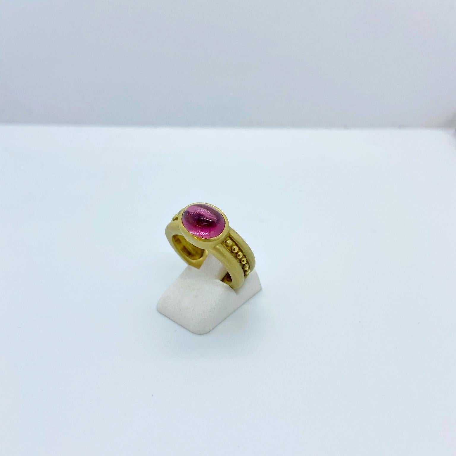 An 18 karat yellow gold ring designed with an oval cabochon pink tourmaline center. The stone is set east /west on a matte shank detailed with gold beads.
Stamped 750
Finger size 6.25