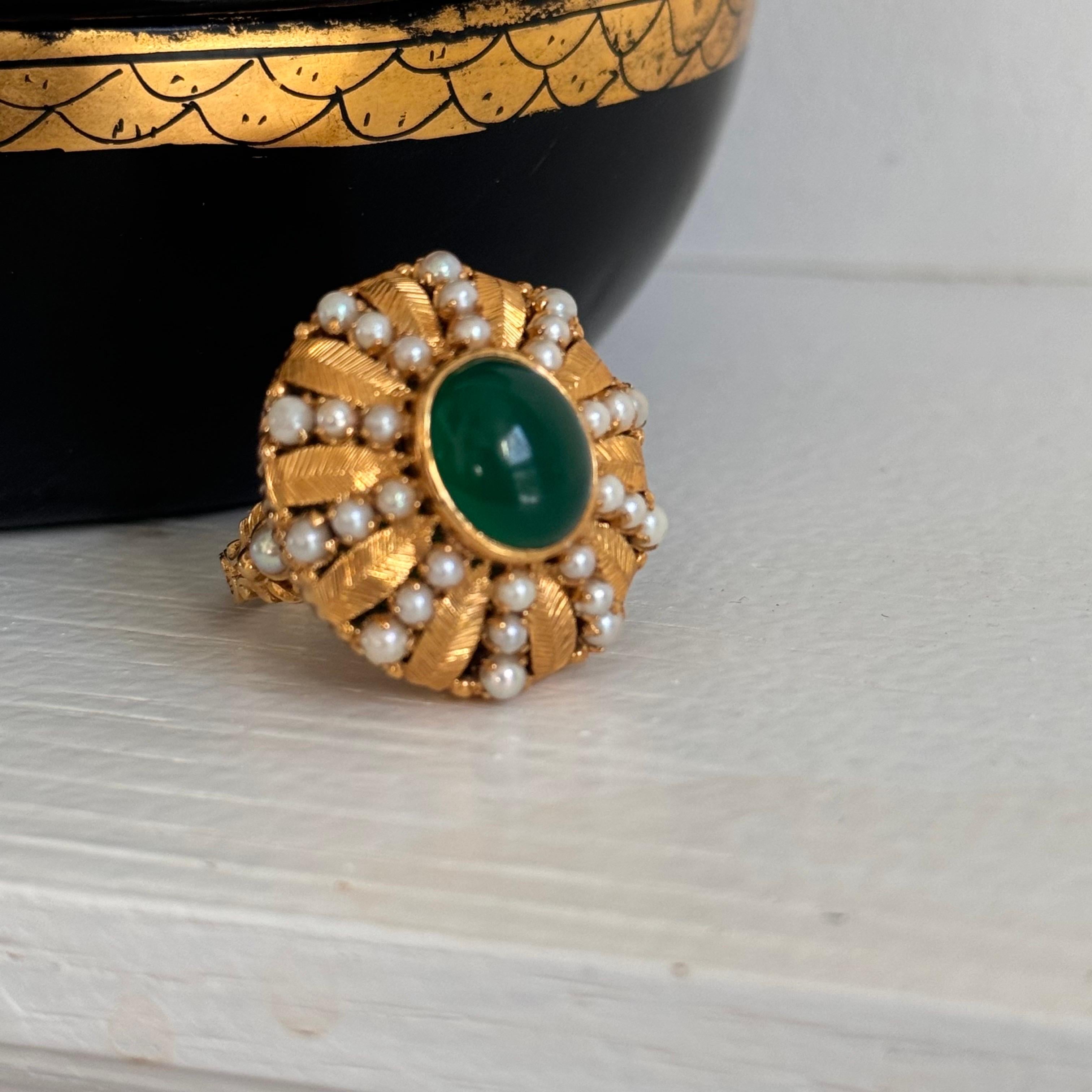 Cette exquise bague ancienne présente un cabochon central de pierre précieuse verte, probablement une chrysoprase, mesurant approximativement 9,0 mm x 11,0 mm. La pierre précieuse est magnifiquement encadrée par une alternance de bandes effilées de