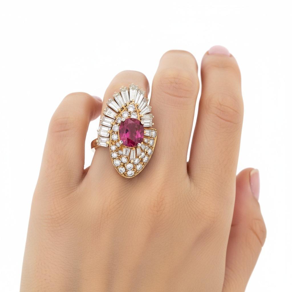 Cette impressionnante bague de cocktail est fabriquée de manière experte en or jaune 18 carats et sertie au centre d'un rubis ancien de taille ovale d'environ 2,10 carats, rayonnant d'une couleur riche et d'une allure vintage. La pièce centrale est
