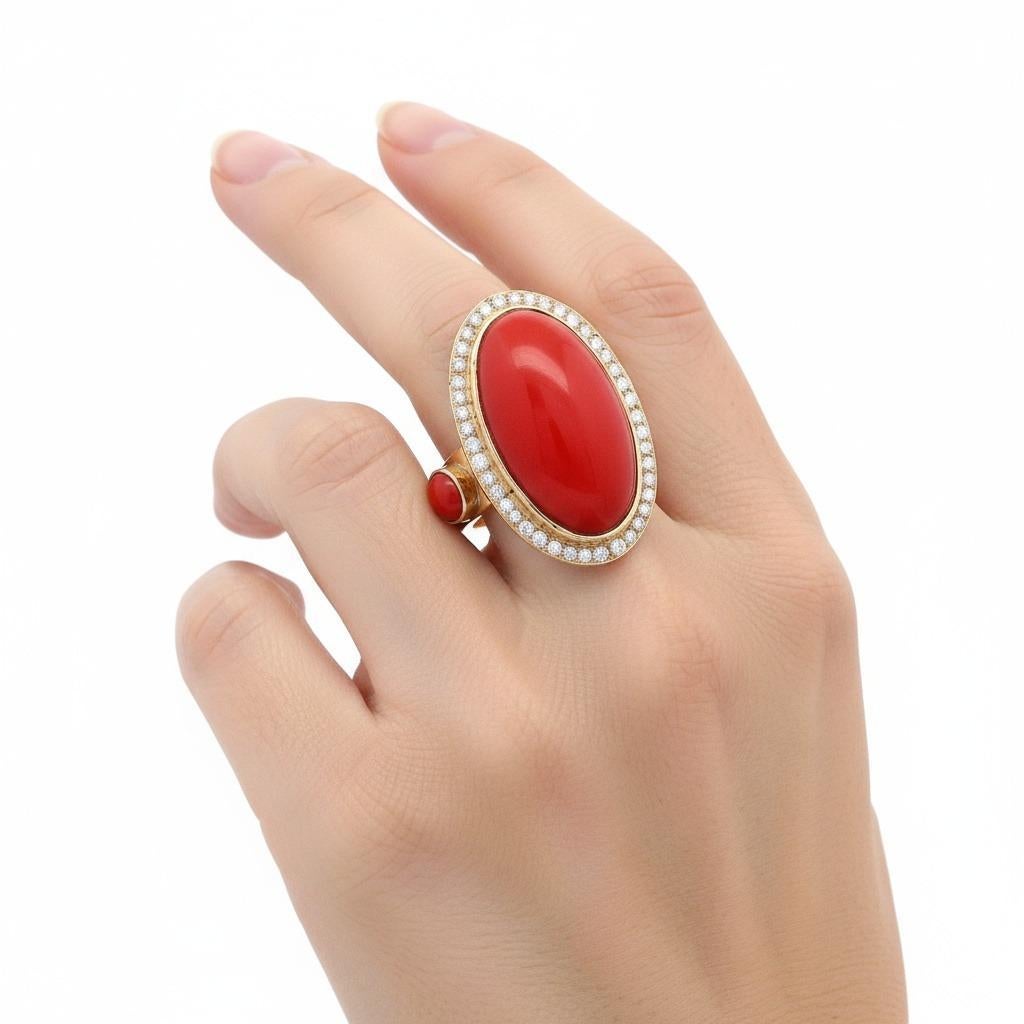 Questo sorprendente anello da cocktail mette in mostra la vibrante bellezza del corallo rosso naturale, sapientemente realizzato in oro giallo 18 carati e incastonato al centro con un impressionante corallo rosso cabochon di circa 30,50 carati. Il