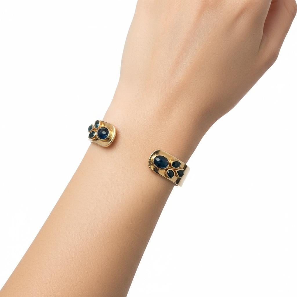 Questo squisito bracciale in oro giallo 18 carati presenta un'armoniosa miscela di gemme naturali, accentuata da due zaffiri blu cabochon, quattro zaffiri blu dal taglio ovale e due zaffiri blu dal taglio a pera per un totale di circa 8,50 carati. A