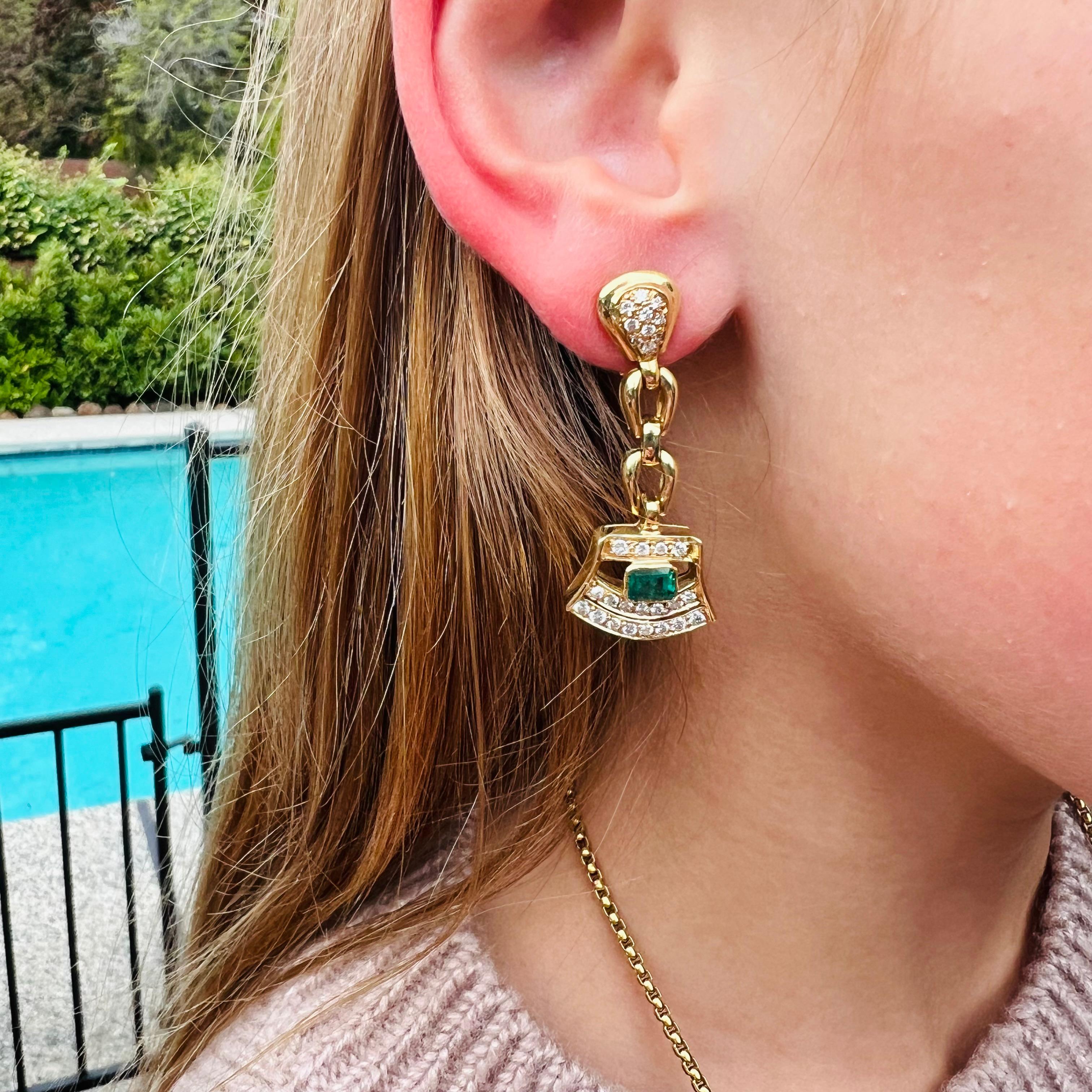 The perfect pop of green! These 18 karat yellow gold drop estate earrings feature a pair of fine emerald cut emeralds weighing a total of 1.10 carats bezel set and surrounded by approximately 1.00 carats of fine white natural diamonds, suspended