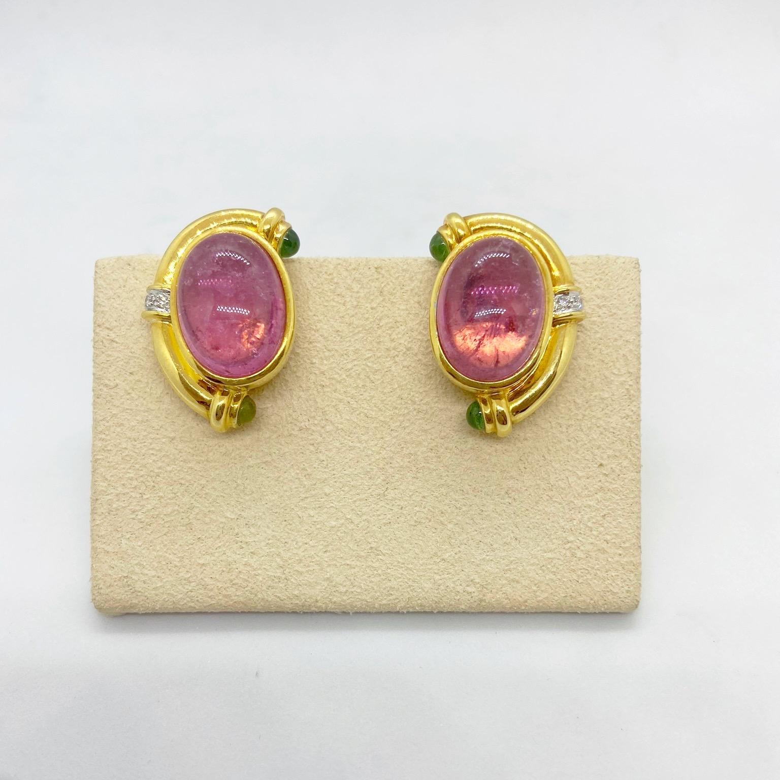 These earrings center large oval Pink Tourmaline Cabochons in a polished 18 karat yellow gold setting. The earrings are accented with Diamonds and Green Tourmaline Cabochons.T hey measure 1 1/8