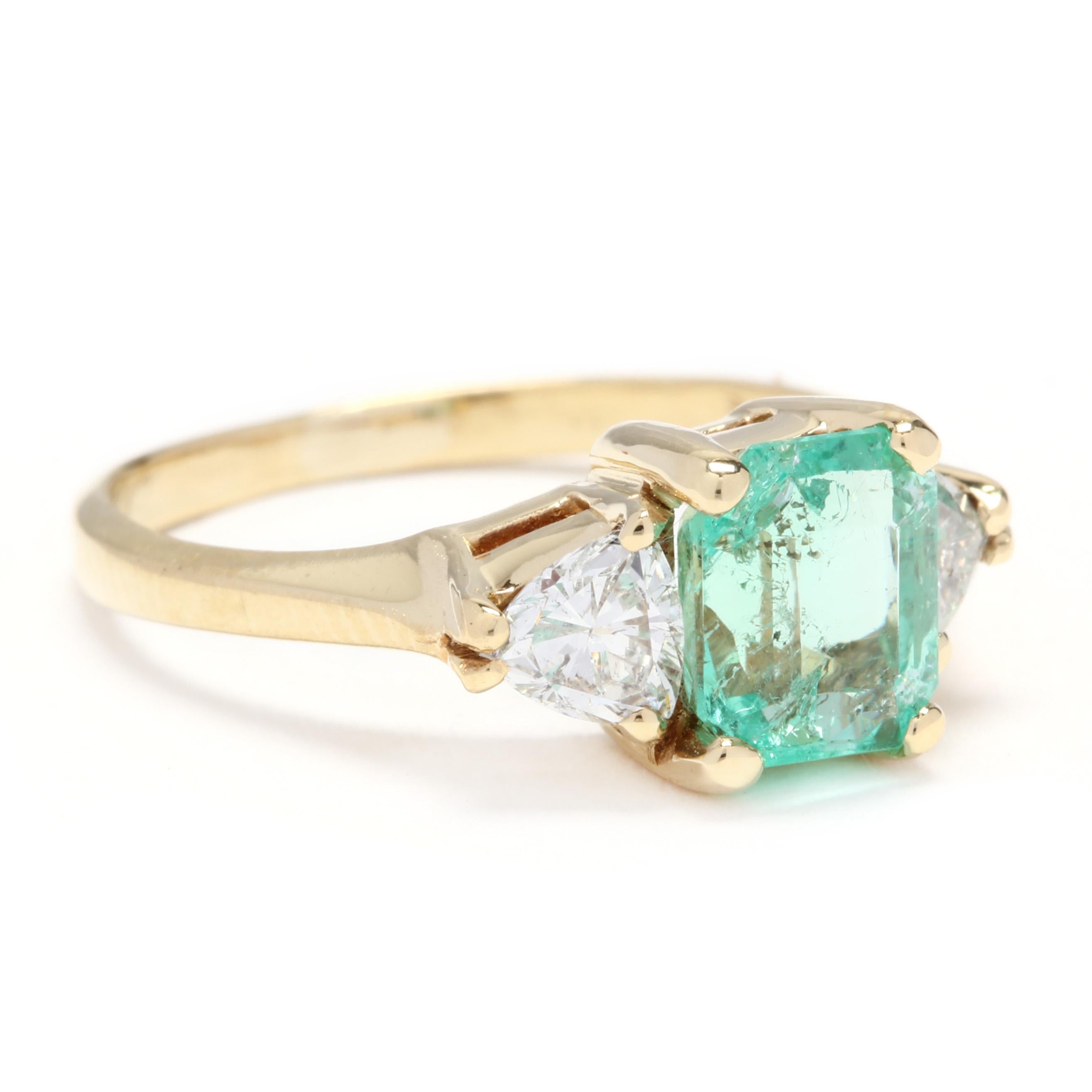An 18 karat yellow gold, emerald and trillion diamond three stone ring. Centered on a prong set, emerald cut emerald weighing approximately 1.30 carat with a prong set, trillion cut diamond on either side weighing approximately .50 total carats and