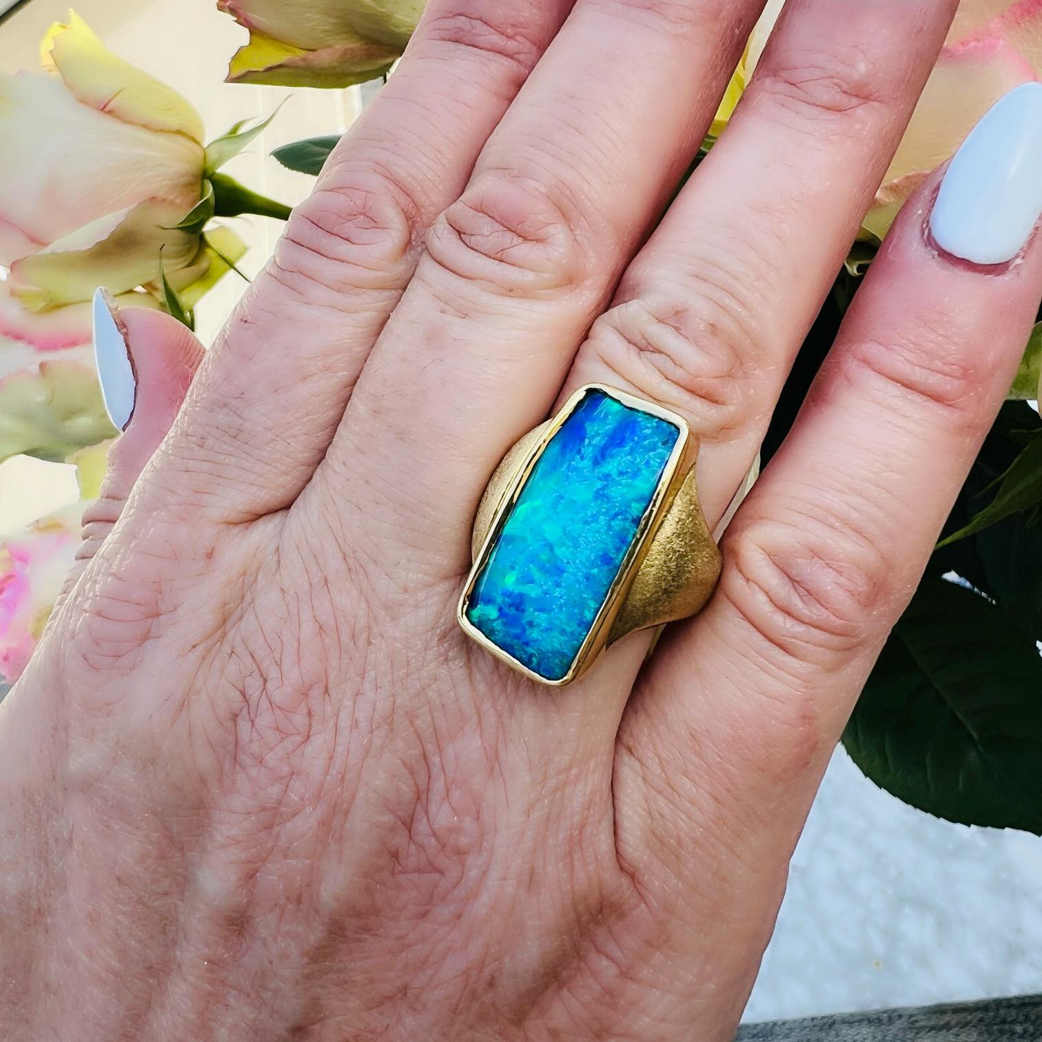 Perhaps the perfect opal ring for those who appreciate the finer things! This 18 karat yellow gold custom ring features a phenomenal peacock play of color natural Australian boulder opal that flashes with intense blues and greens throughout. The