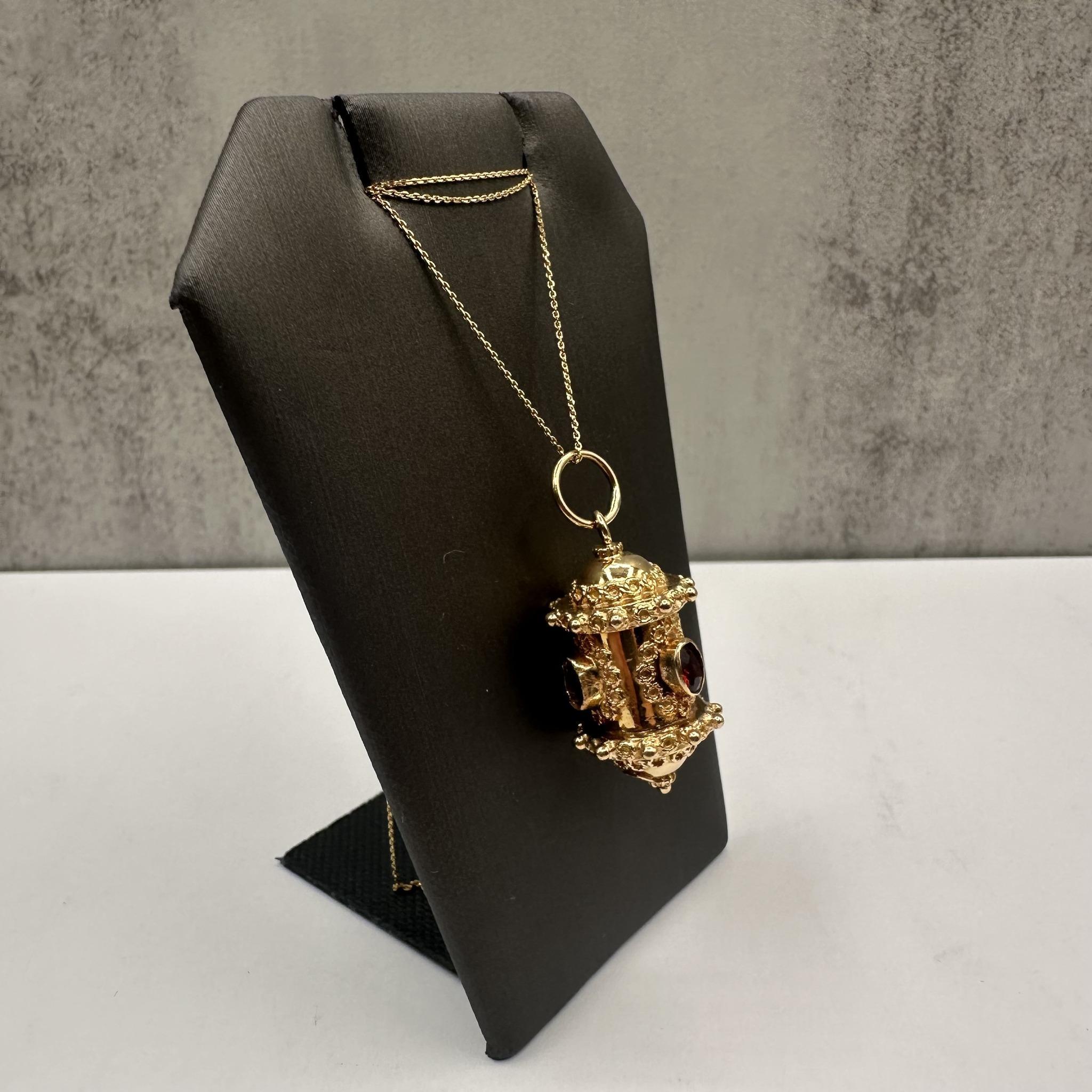 Diese wunderschöne Granat-Halskette aus 18-karätigem Gelbgold ist mit 4 atemberaubenden Granaten verziert, die in komplizierten Lünetten im etruskischen Stil gefasst sind und dem Schmuckstück ein reiches und historisches Design verleihen. Die Kette