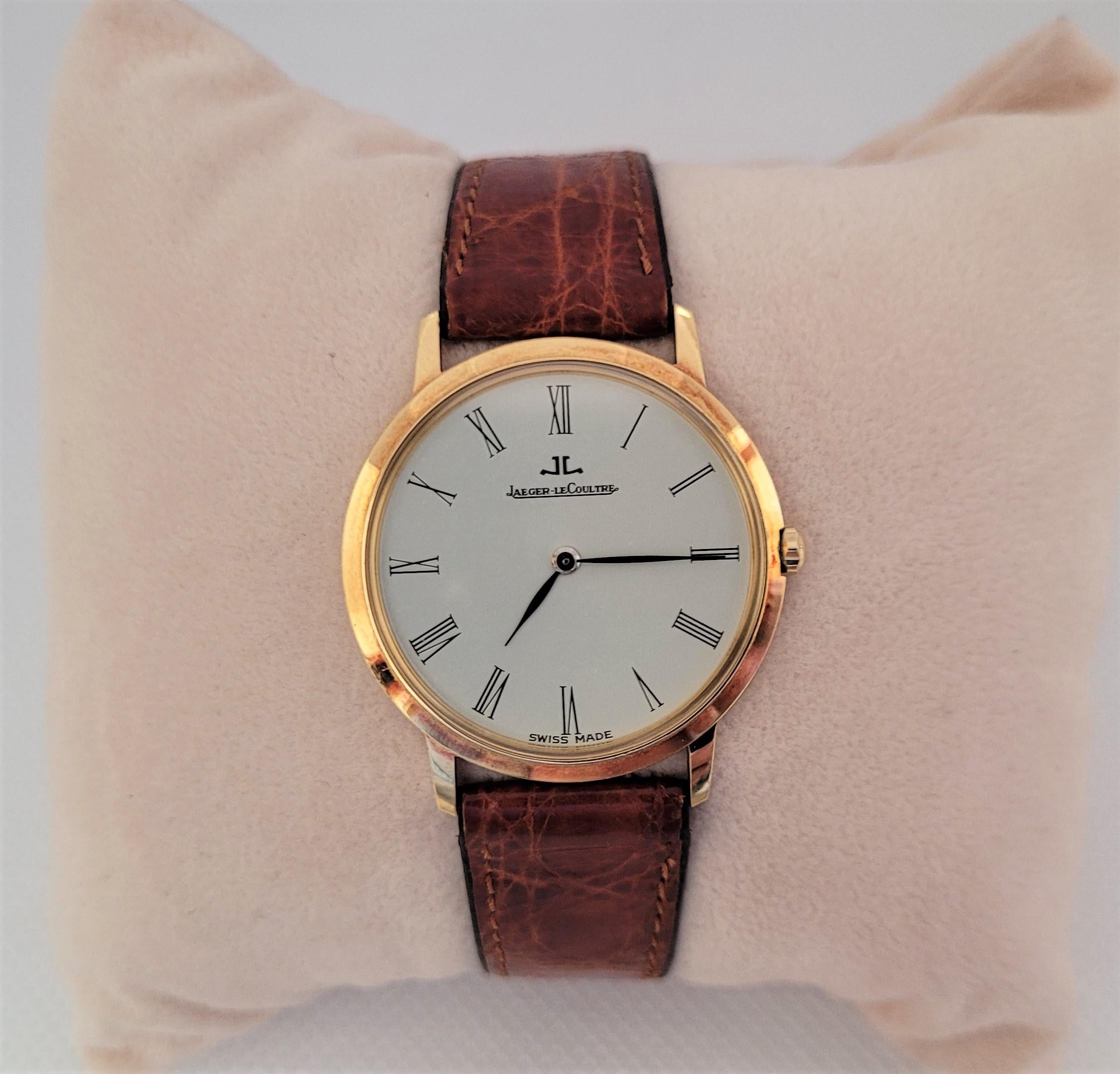 Gorgeous 1990s 18kt yellow gold Jaeger LeCoultre watch with a 30mm case that has a white face with a very clean glass crystal. The case is 4mm thick and stamped on the back 141.117.1 1605511. The manual movement is in good working condition and has