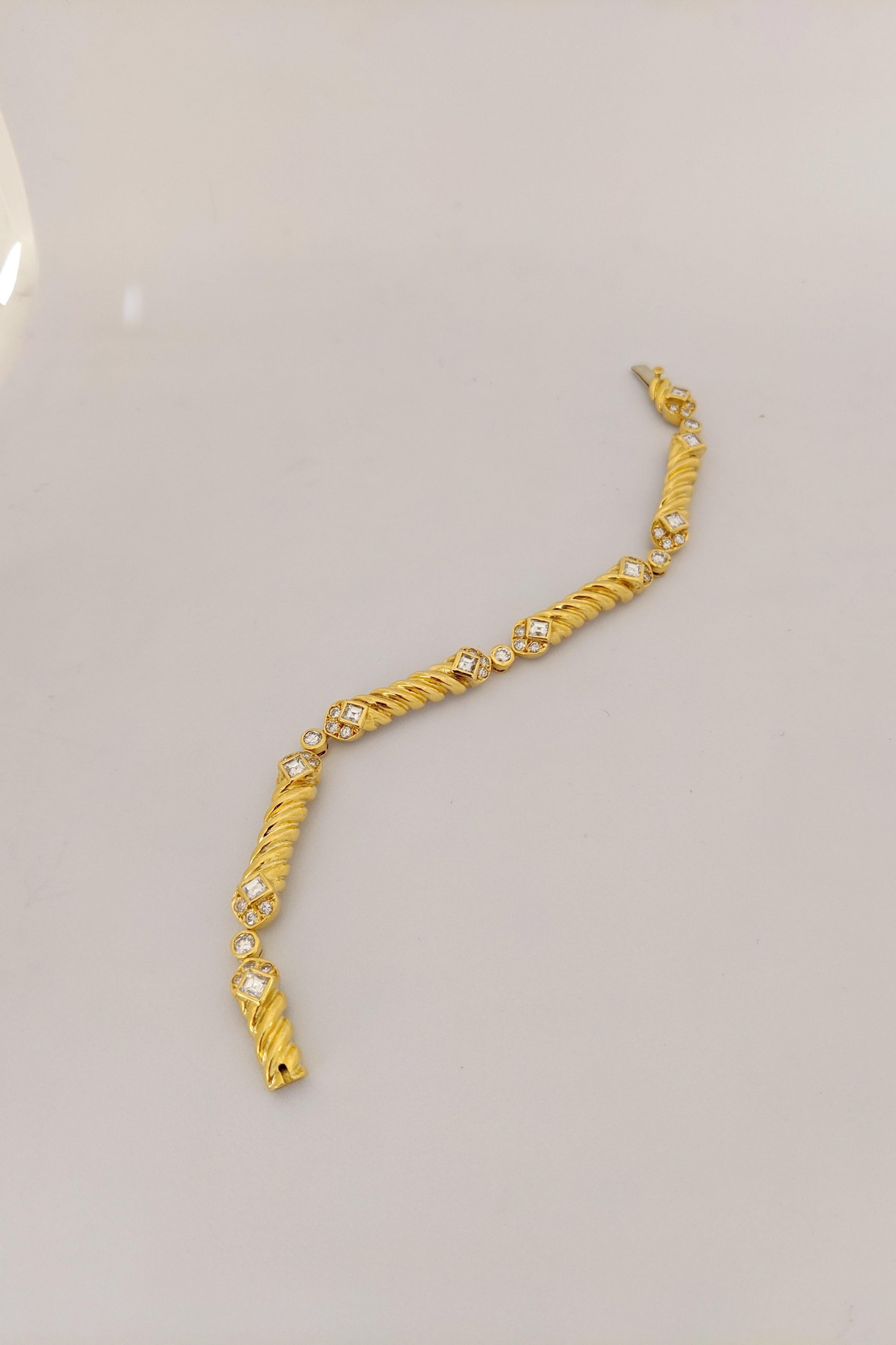 Dieses Armband ist mit 5 gerippten Gliedern aus 18 Karat Gelbgold gestaltet. Jedes Glied ist mit 6 runden Brillanten und 2 quadratischen Diamanten im Smaragdschliff besetzt. Die Glieder sind dann mit runden, eingefassten Diamanten verbunden. Das