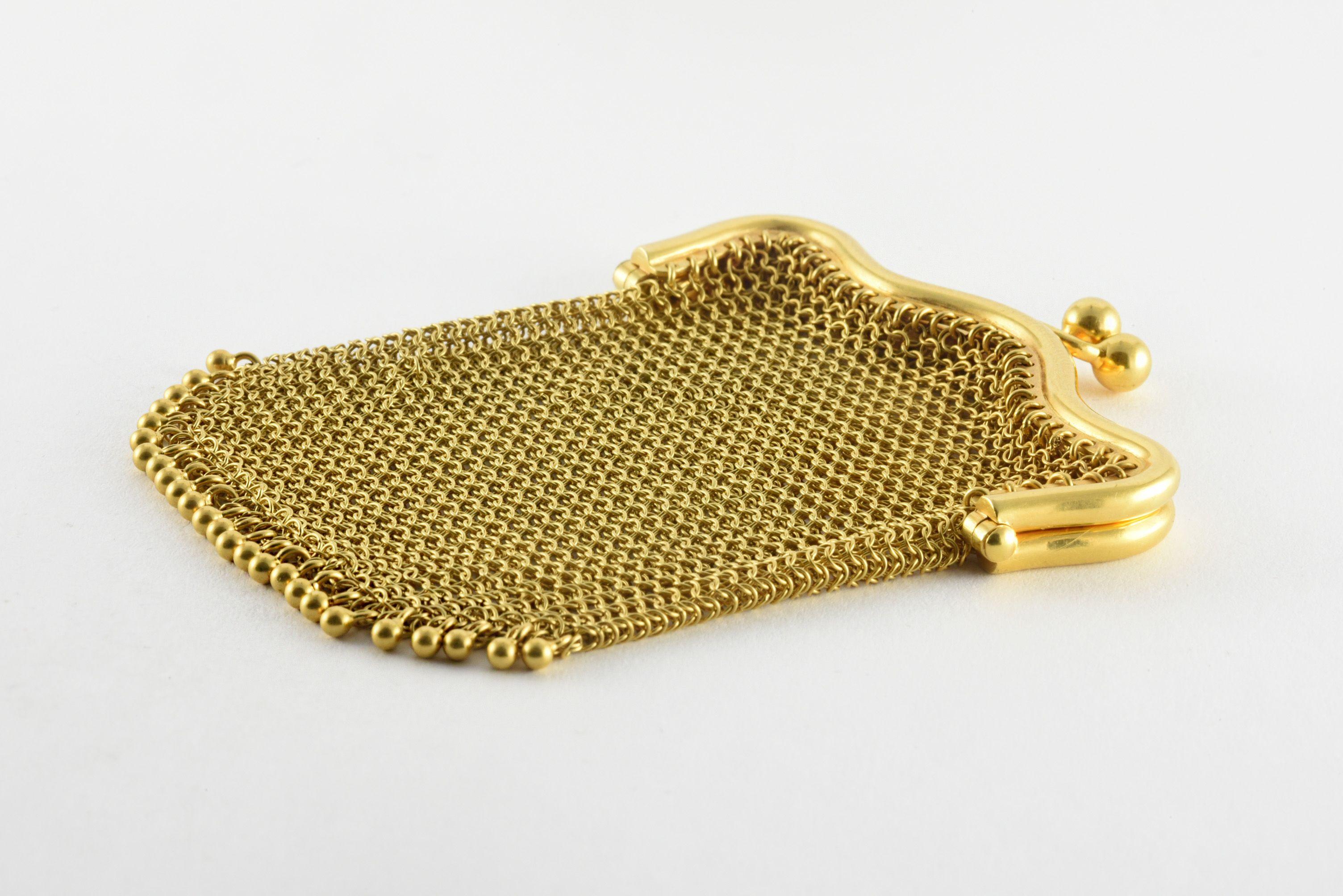 This antique mini mesh clutch fashioned from 18kt yellow gold features a kiss lock fastener and decorative “fringe” at the bottom. It is likely from the turn of the twentieth century as mesh bags like these were made popular in the early 1880s. This