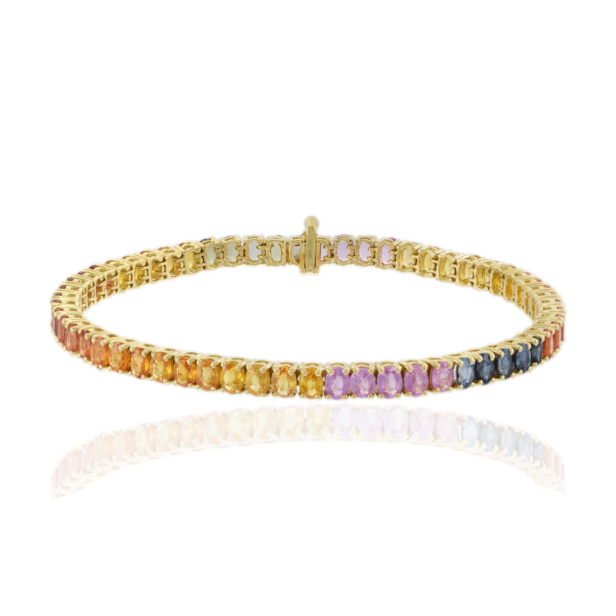 Exquisitely crafted in 18k yellow gold, this tennis bracelet showcases a vibrant array of oval-cut sapphires in a stunning rainbow palette. Each sapphire is meticulously set, creating a seamless flow of color around the wrist. Interspersed with