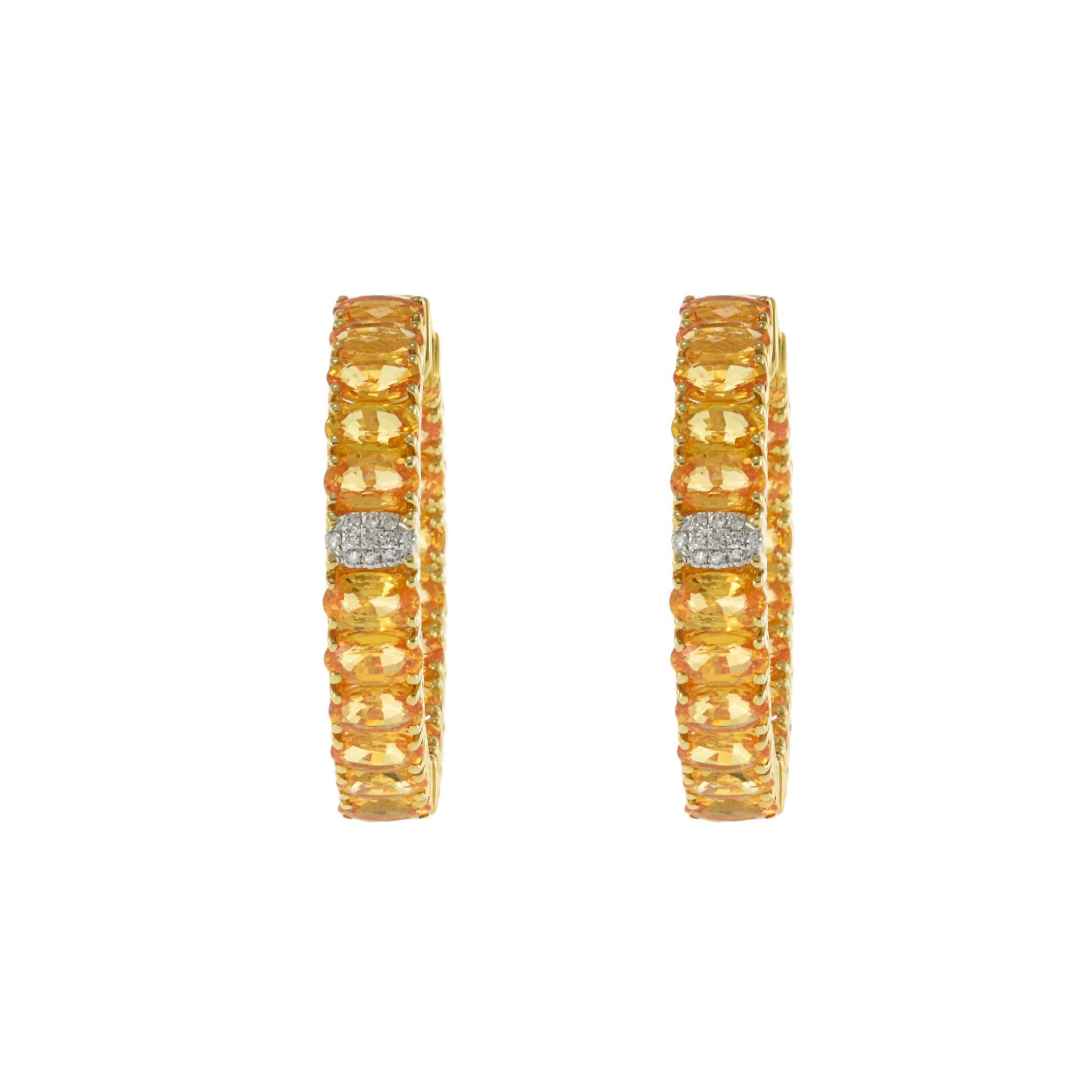 These elegant hoop earrings feature 12.07 carats of vibrant oval yellow sapphires, beautifully set in 18KT yellow gold. Accentuated by 0.08 carats of sparkling round-cut diamonds, these earrings offer a striking combination of color and brilliance,