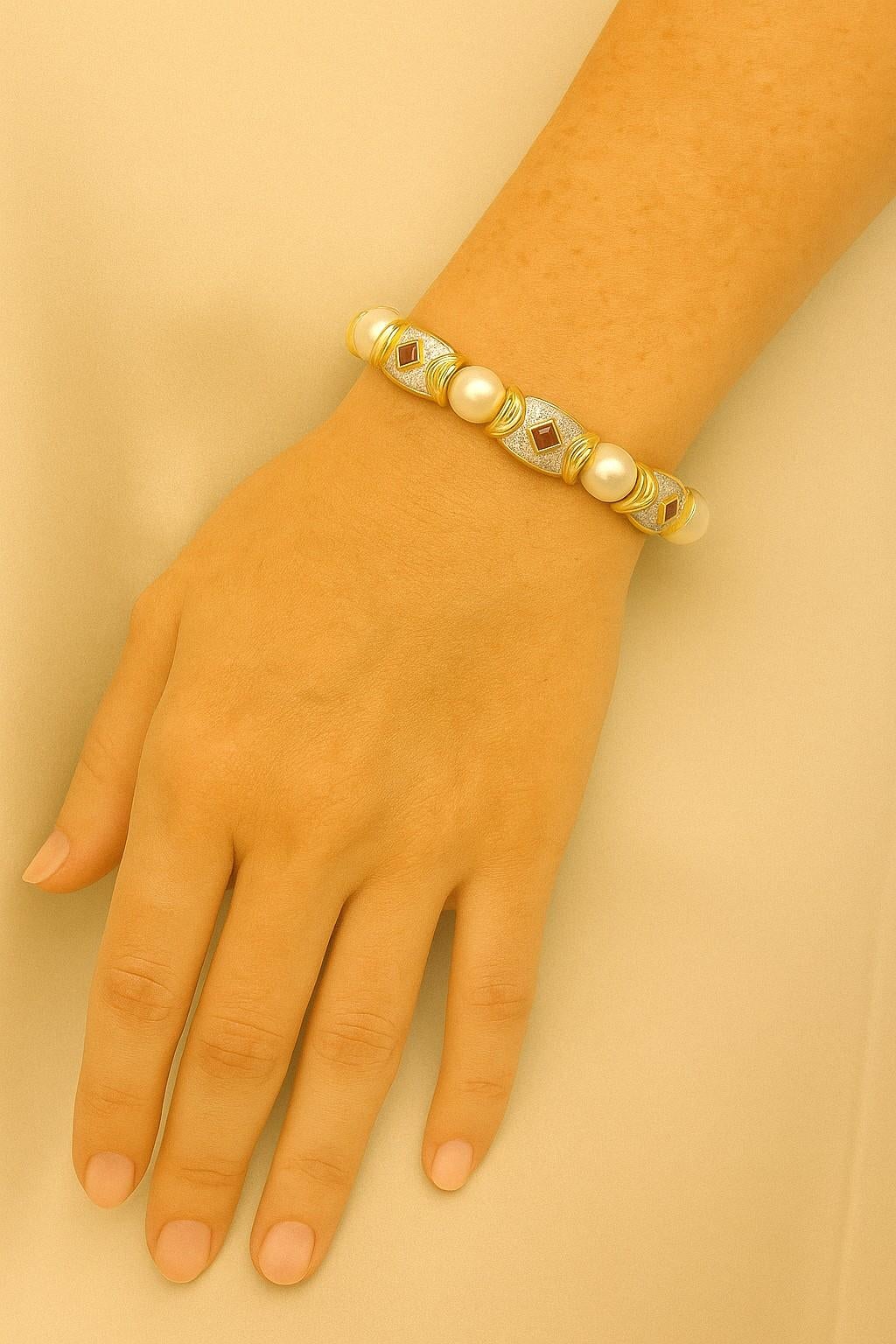 18kt Yellow Gold Pearl, Diamond, and Ruby Flexible Cuff Bangle
This elegant flexible cuff bangle is masterfully crafted in 18kt yellow gold, combining classic sophistication with luxurious detail. The design features seven lustrous pearls, each