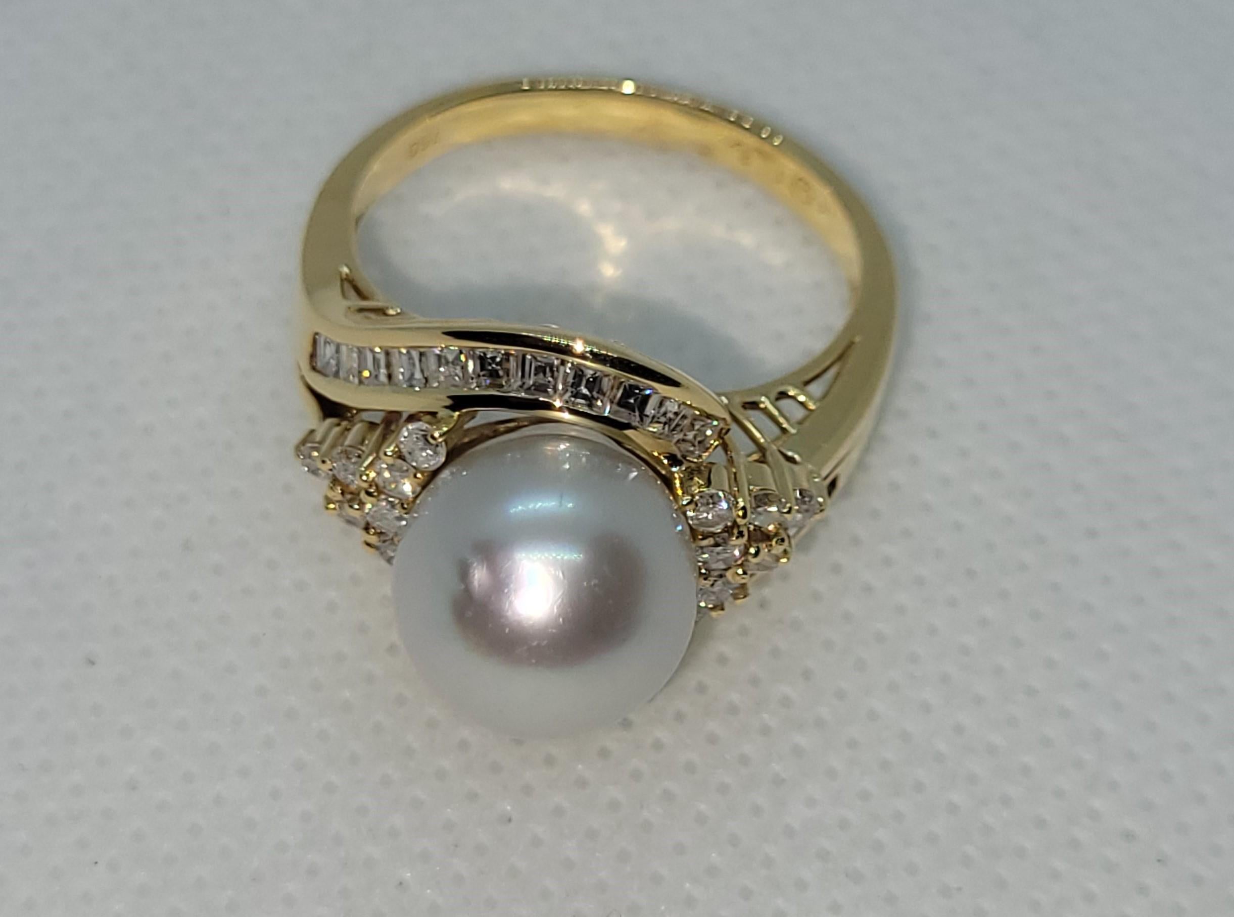 This exquisite 18kt yellow gold ring showcases a stunning 10.5mm silver-white pearl, surrounded by a glorious array of diamonds. The ring features a total of 22 baguette-cut diamonds and 14 round brilliant diamonds with an approximate total carat