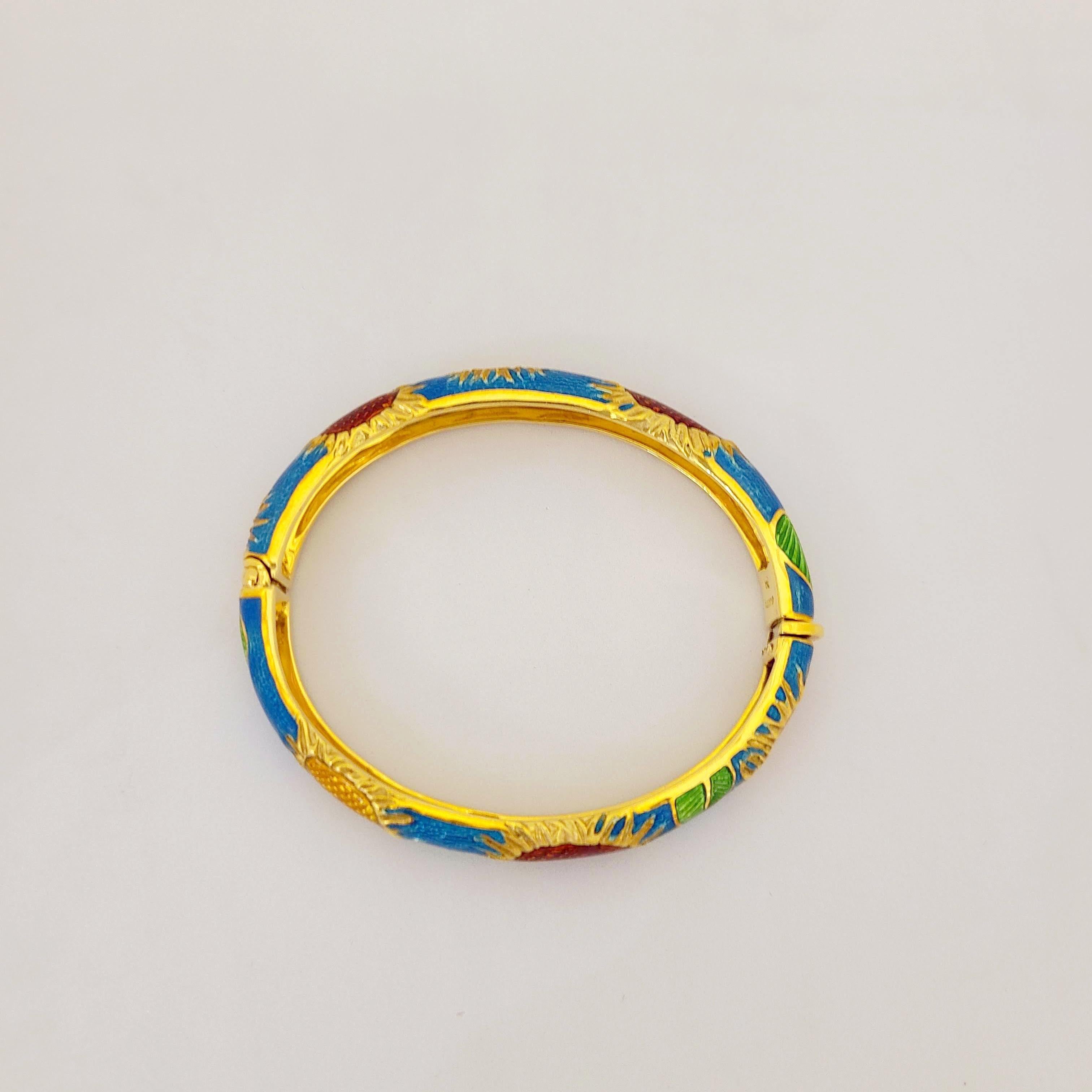 This 18 karat yellow gold oval shaped bracelet is enameled in a medium vibrant blue. Red and yellow enamel sunflowers with green leaves are the overall design. The inside measurement of the bangle is 56.5mm x 47.5 mm ...2.5