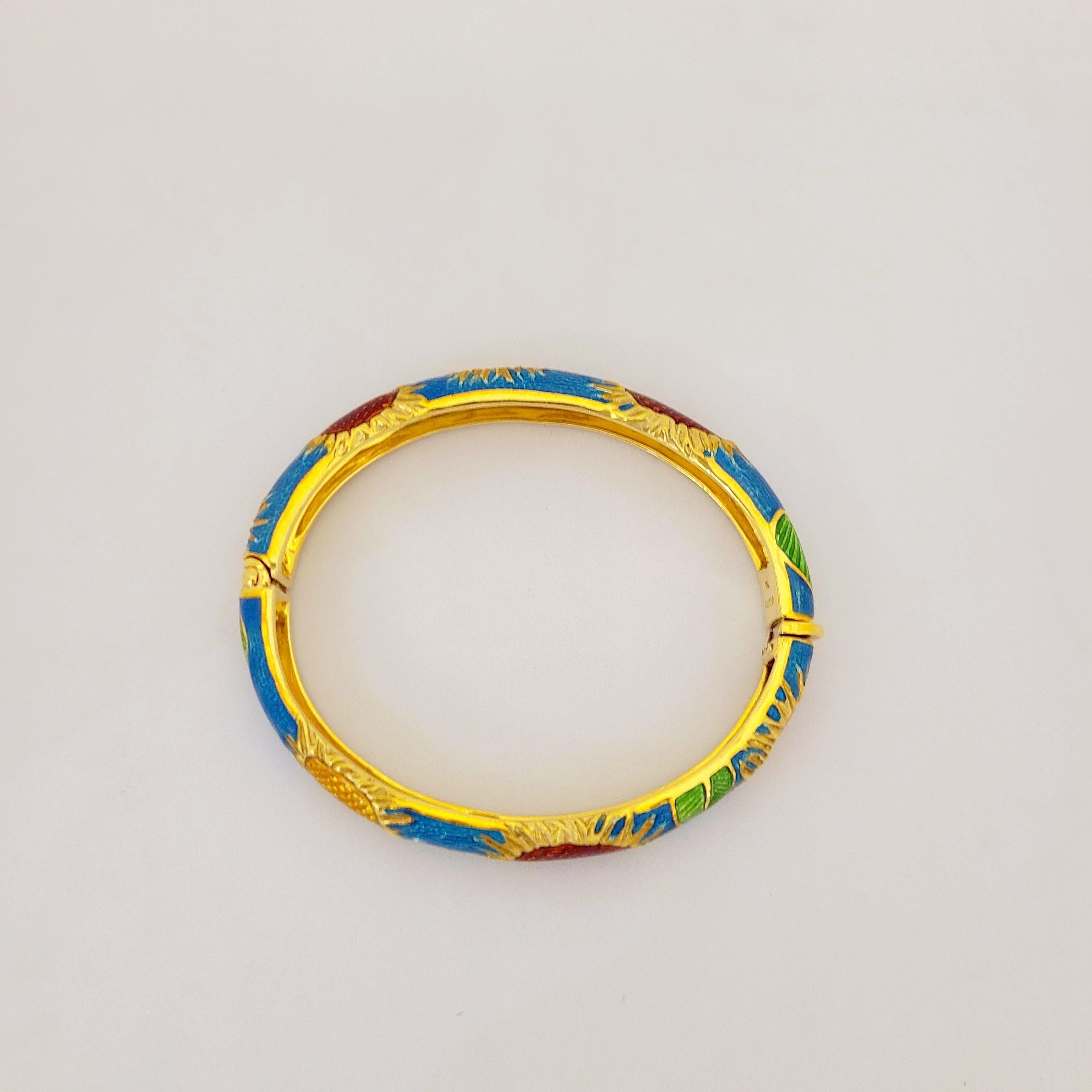 Dieses ovale Armband aus 18 Karat Gelbgold ist in einem mittleren, leuchtenden Blau emailliert. Rote und gelbe Emaille-Sonnenblumen mit grünen Blättern bilden das Gesamtdesign. Die Innenmaße des Armreifs sind 56,5 mm x 47,5 mm ...2,5
