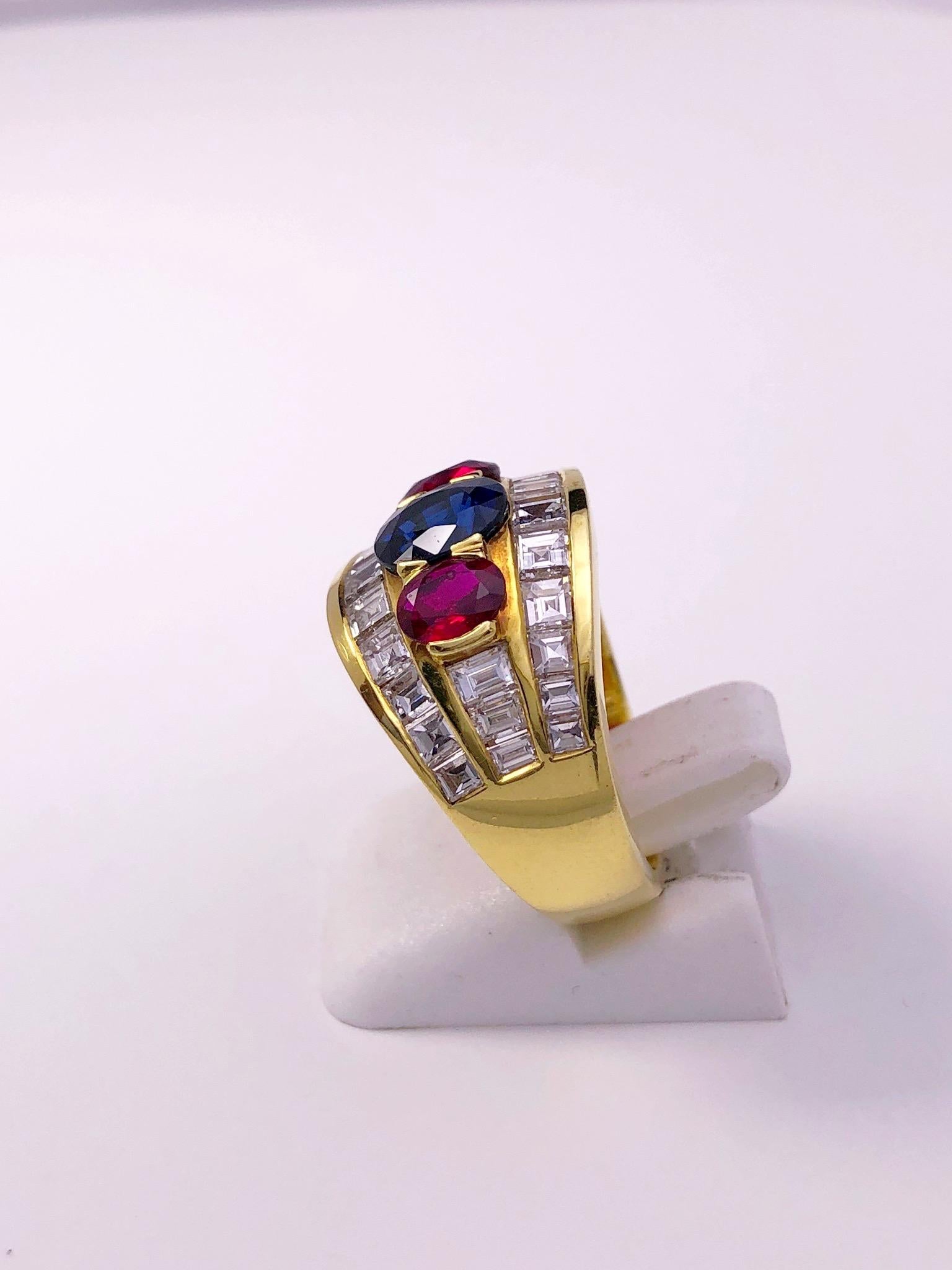 This 18KT. yellow gold ring centers an oval Blue Sapphire flanked on either side by oval Rubies. The 3 stones are set amid 3 rows of Calibre (square) cut diamonds.
Sapphire 1.53 carats
Rubies 0.92 carats
Diamonds 2.18 carats
Finger size 6.75 sizing