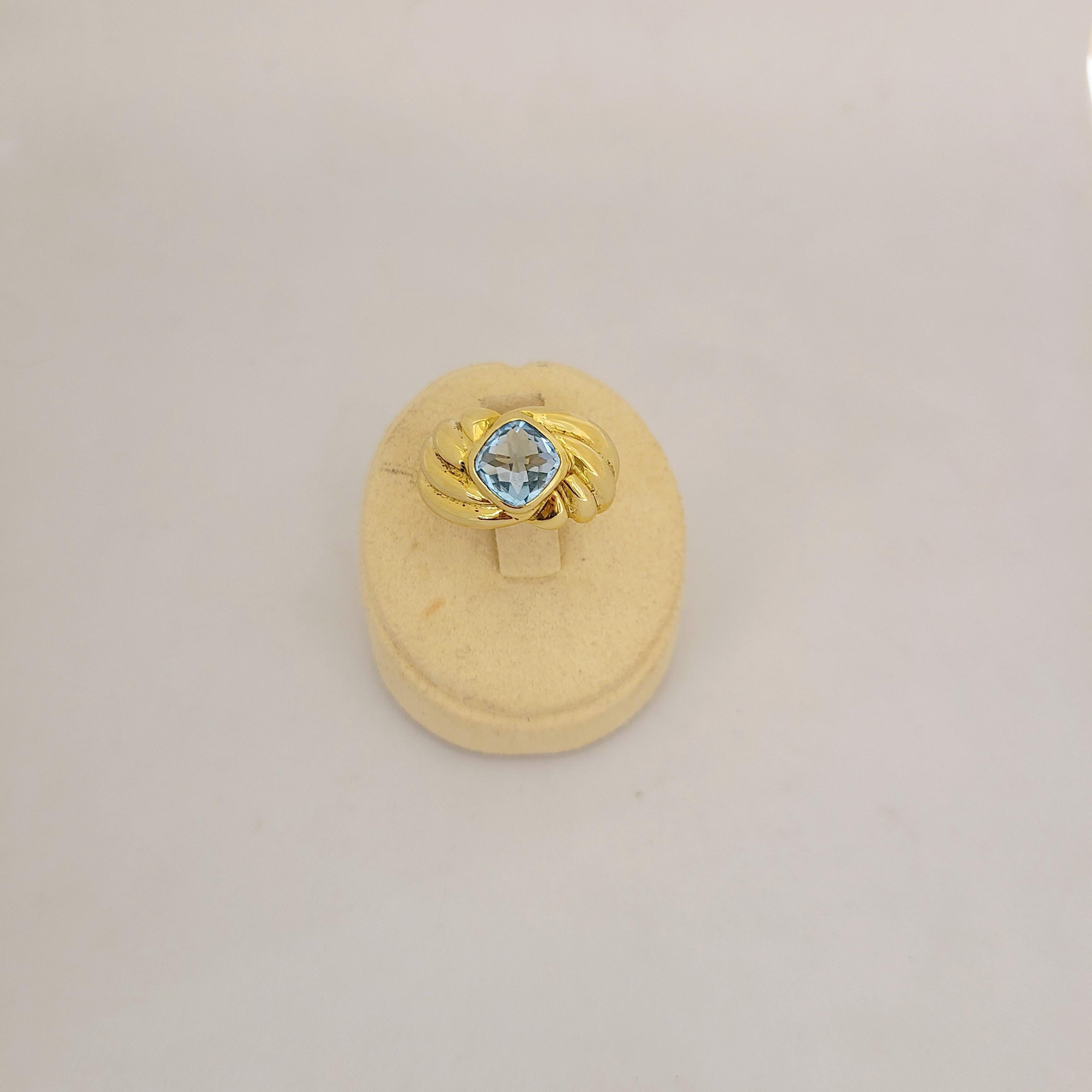 Dieser Ring aus 18-karätigem Gelbgold ist mit einem kissenförmigen blauen Topas als Briolettstein besetzt. Der in der Lünette gefasste Stein sitzt auf dem Schaft, der mit einer durchgehenden Riffelung versehen ist.
Blauer Topas Gesamtgewicht 2,80