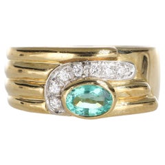 Anillo de oro amarillo de 18 quilates con esmeralda ovalada y detalle de diamantes pavé