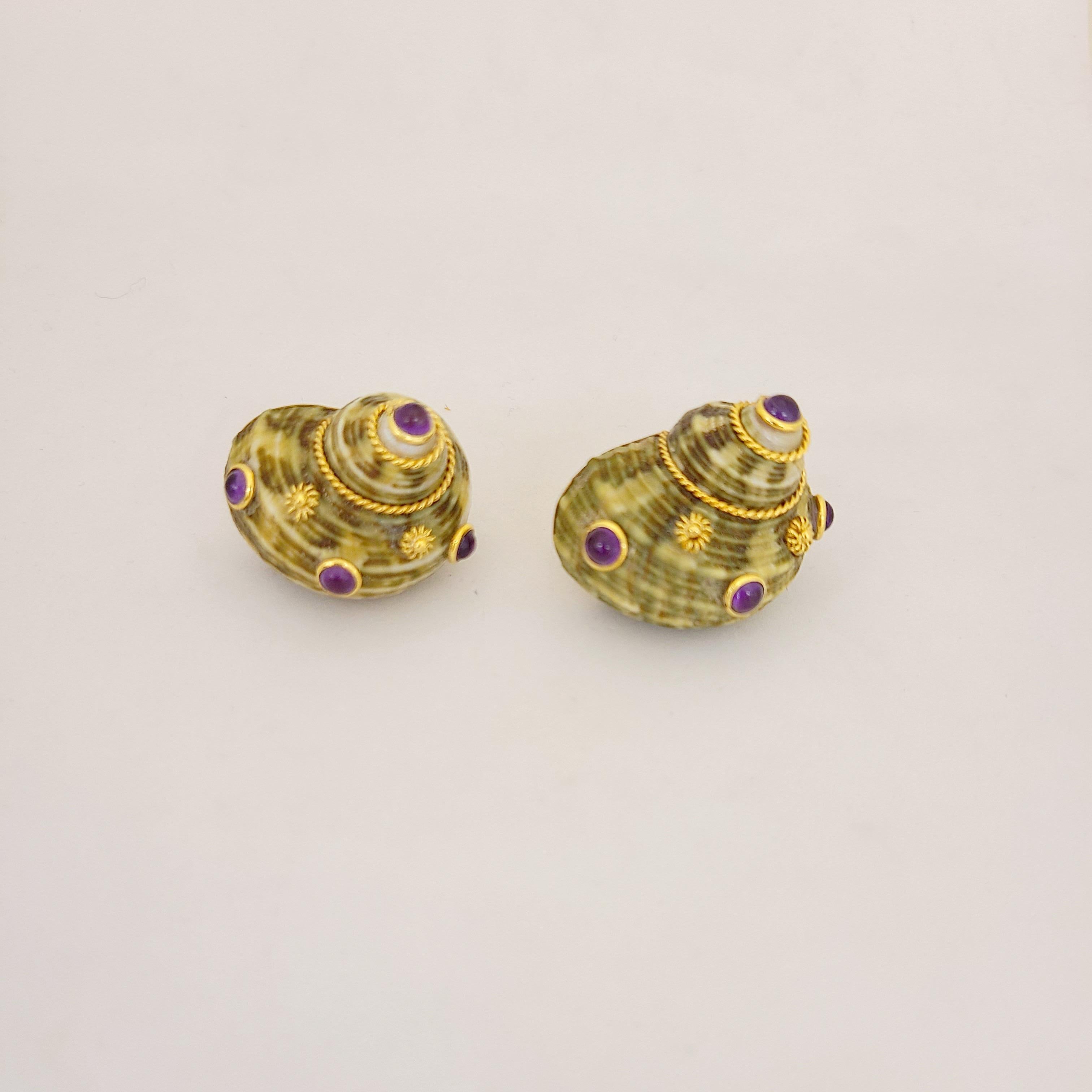 These 18 karat yellow gold earrings are designed with mountings that have been set with green seashells. The shells are decorated with bezel set cabochon amethysts, along with small gold flowers. The earrings have Omega backs, but posts can be added