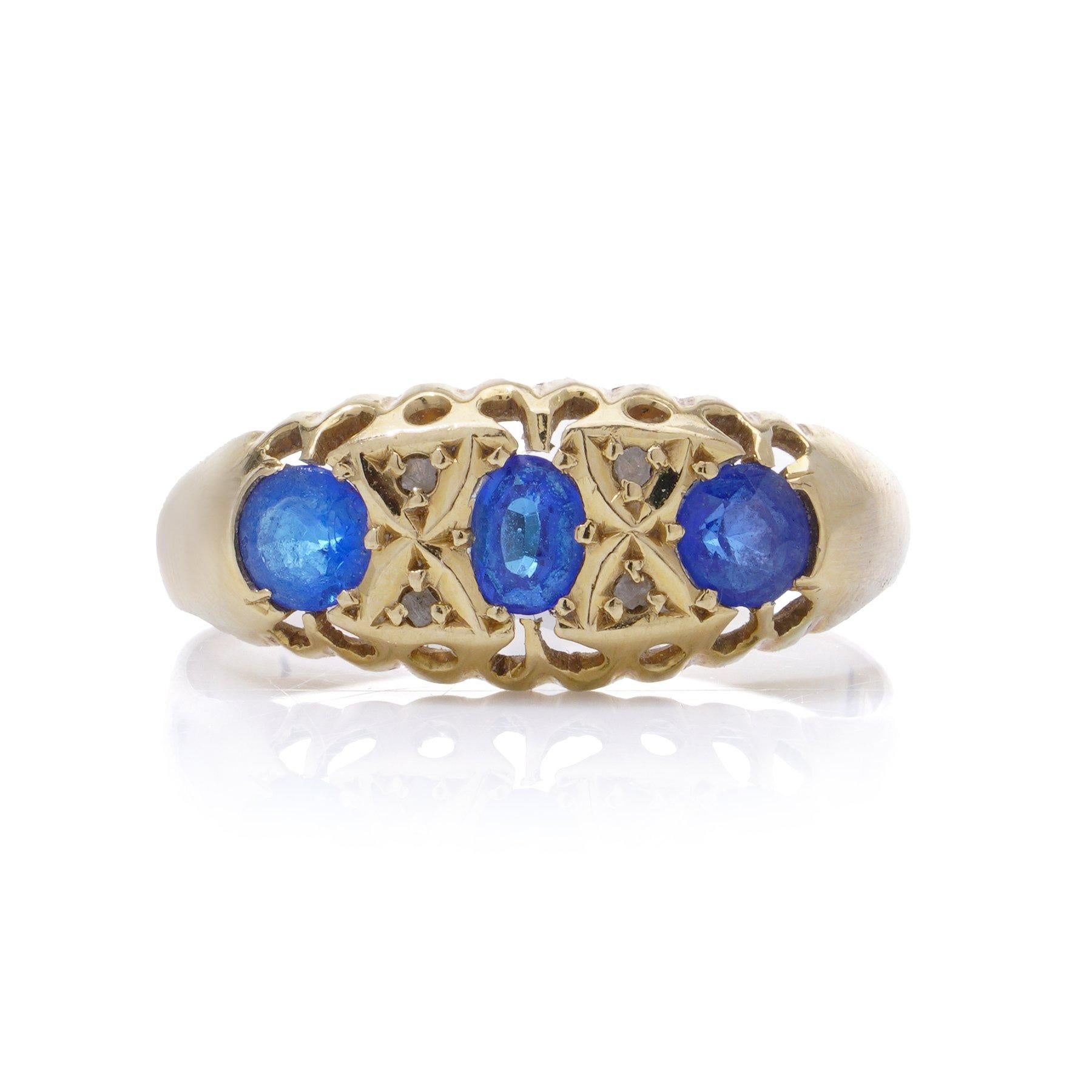 18kt yellow gold three - stone sapphire ring.
Made in England, Sheffield, 1937
Fully hallmarked.

This ring features three blue sapphires set in 18kt yellow gold, accented by geometric gold patterns resembling an X-shaped design between the
