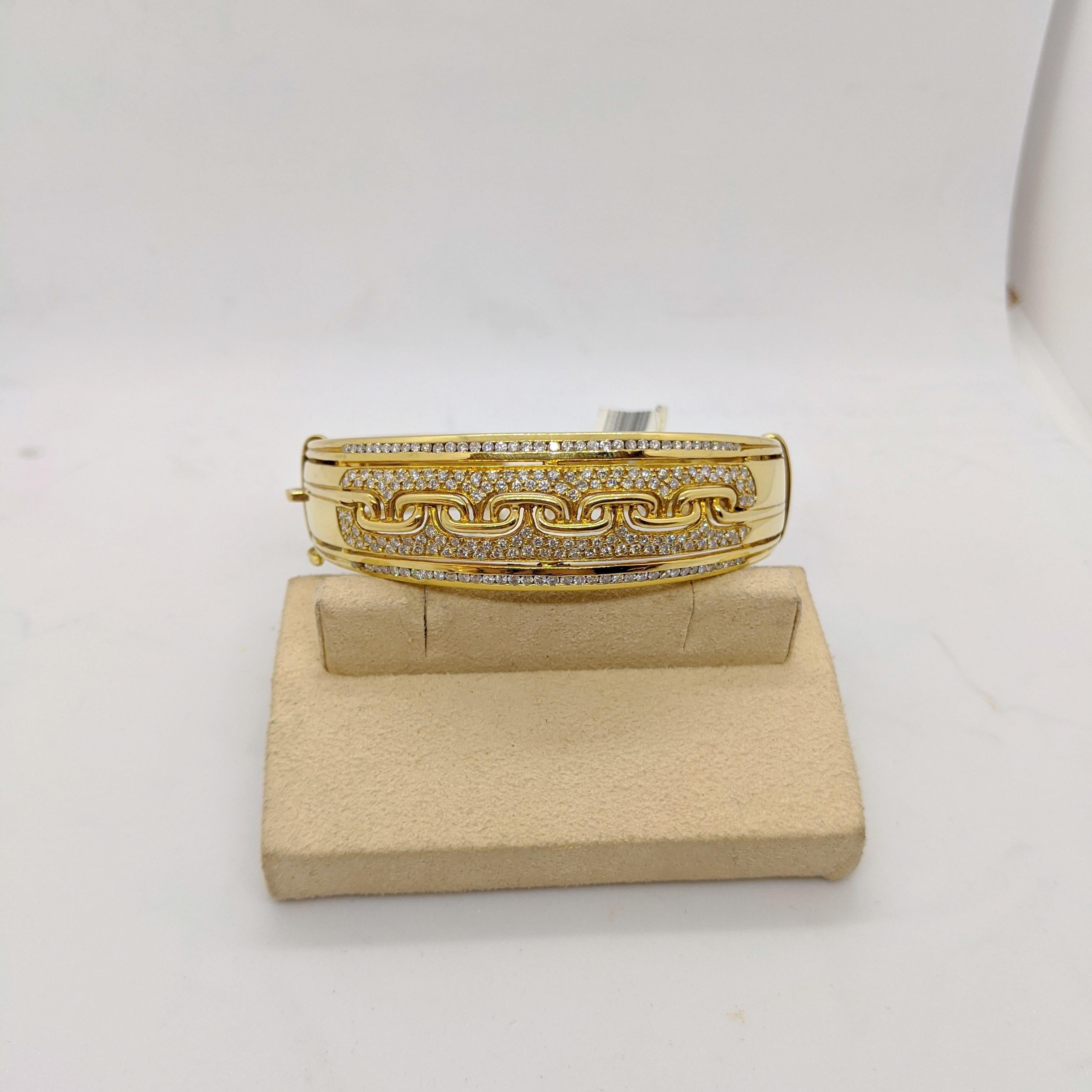 This bracelet is designed in 18 karat yellow gold . It is a wide cuff/bangle. The center of the bracelet is set with  3.32 carats of round brilliants diamonds. A gold link pattern is set across the center. There is a hinge on one side and a plunger