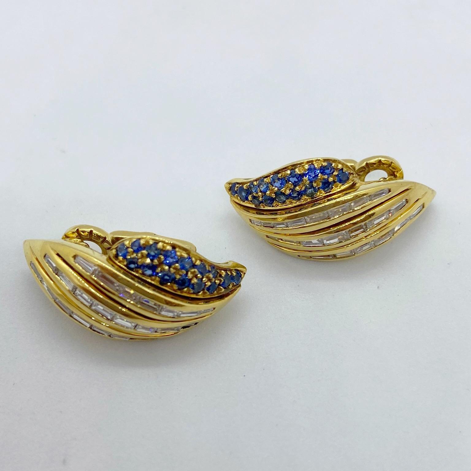 A lovely pair of wing shaped 18 karat yellow gold earrings set with 3 rows of Diamond Baguettes and 2 rows of round Blue Sapphires. The earrings measure 1