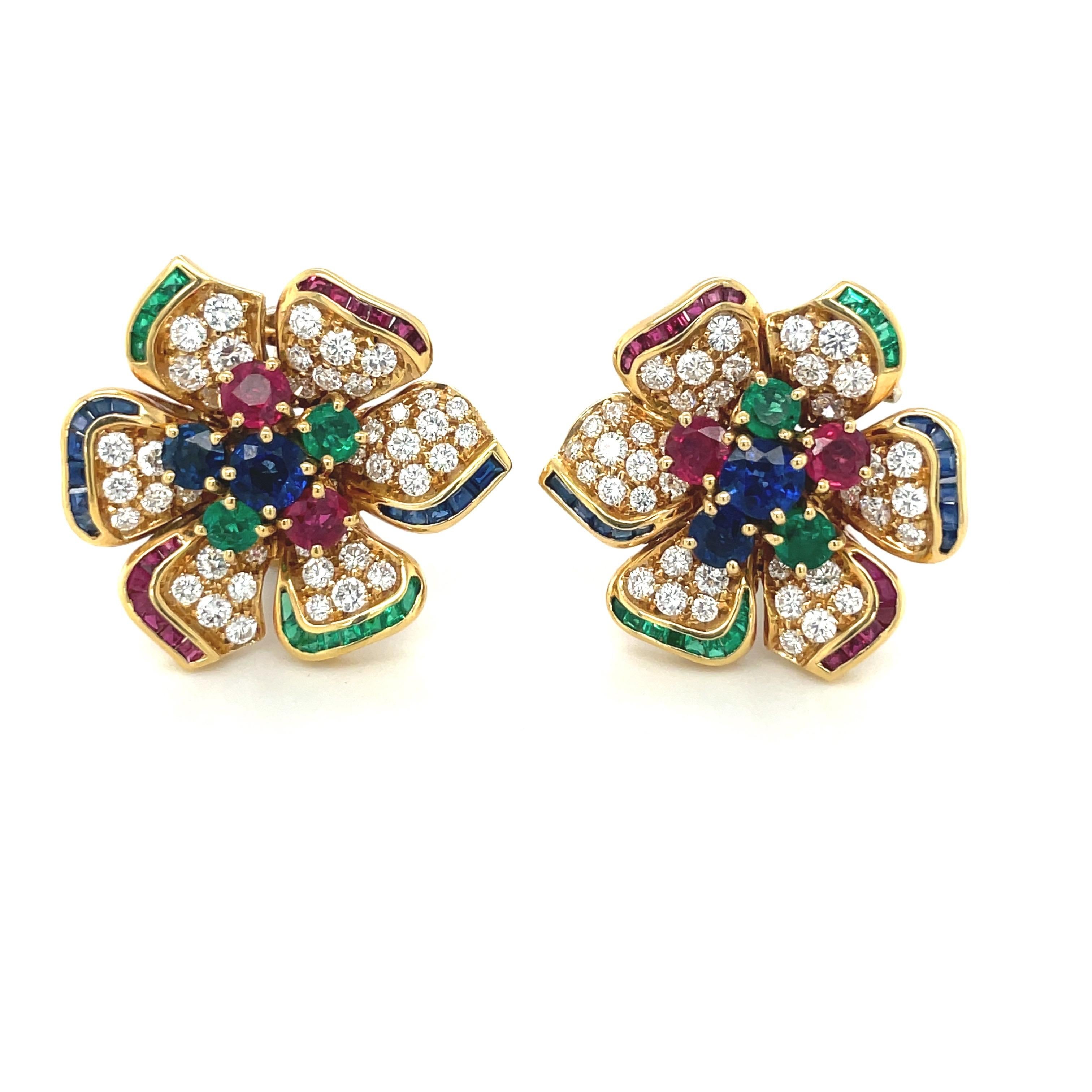 Magnificent 18 karat yellow gold flower earrings. The flowers 6 petals are set with round brilliant diamonds, each tipped with square cut stones in ruby, emerald and sapphires. The center of the earrings are set with round gem stones. This section