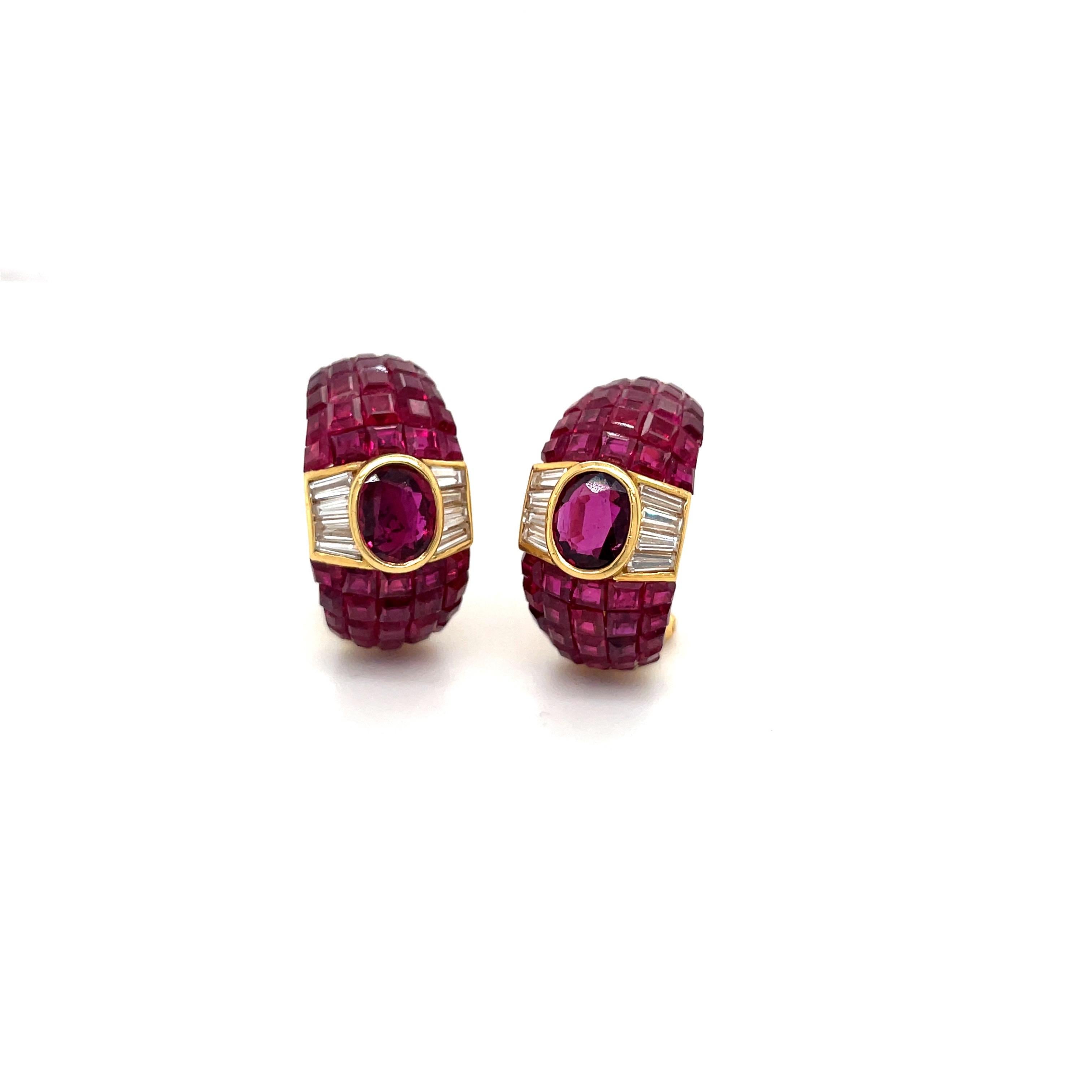 Magnificent 18 karat yellow gold, ruby and diamond half hoop earrings. These stunning earrings center oval bezel set rubies. Tapered diamond baguettes flank the center rubies.The balance of the hoop shaped earrings are set with square invisibly set