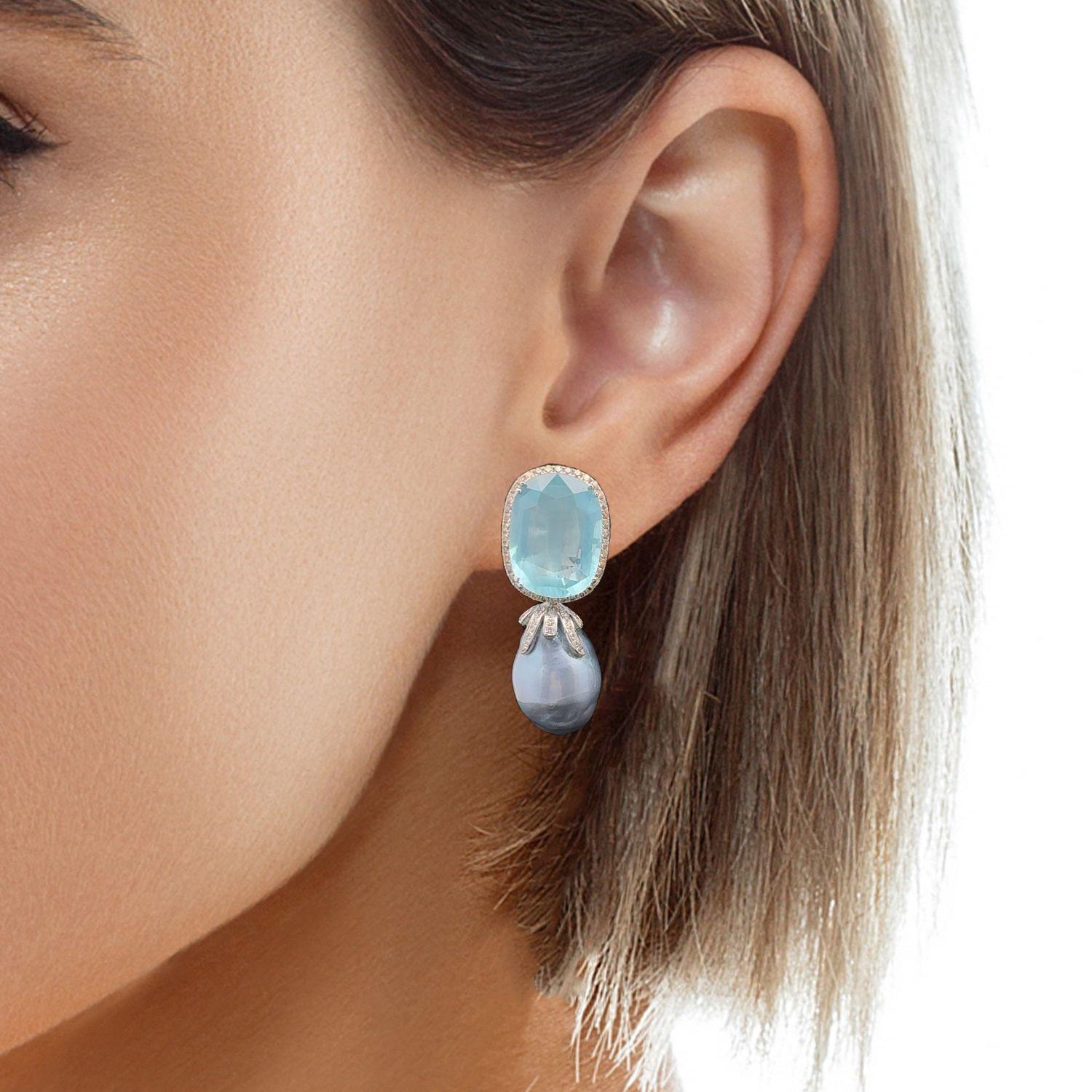 This pair of earrings showcases a stunning combination of elements that make it both fun and elegant. The 18KWG light grey baroque South Sea pearl adds a touch of sophistication, while the pear-shaped and oval aquamarines weighing approximately 32