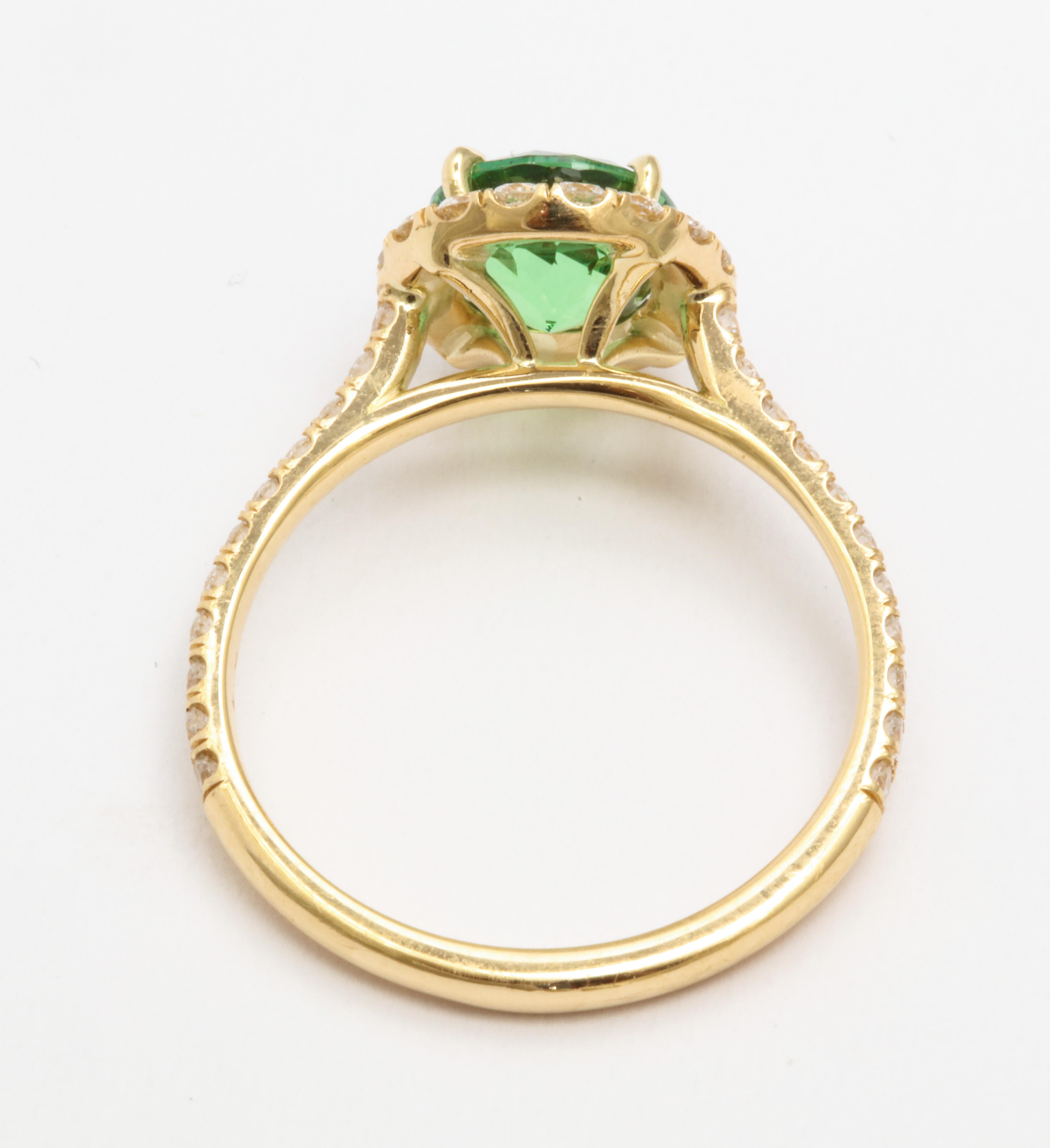 A ring set in 18 karat yellow gold featuring a 1.50 carat round green tsavorite. Surrounded by round brilliant diamonds with a total weight of 0.76 carats. Ring size 6. 
