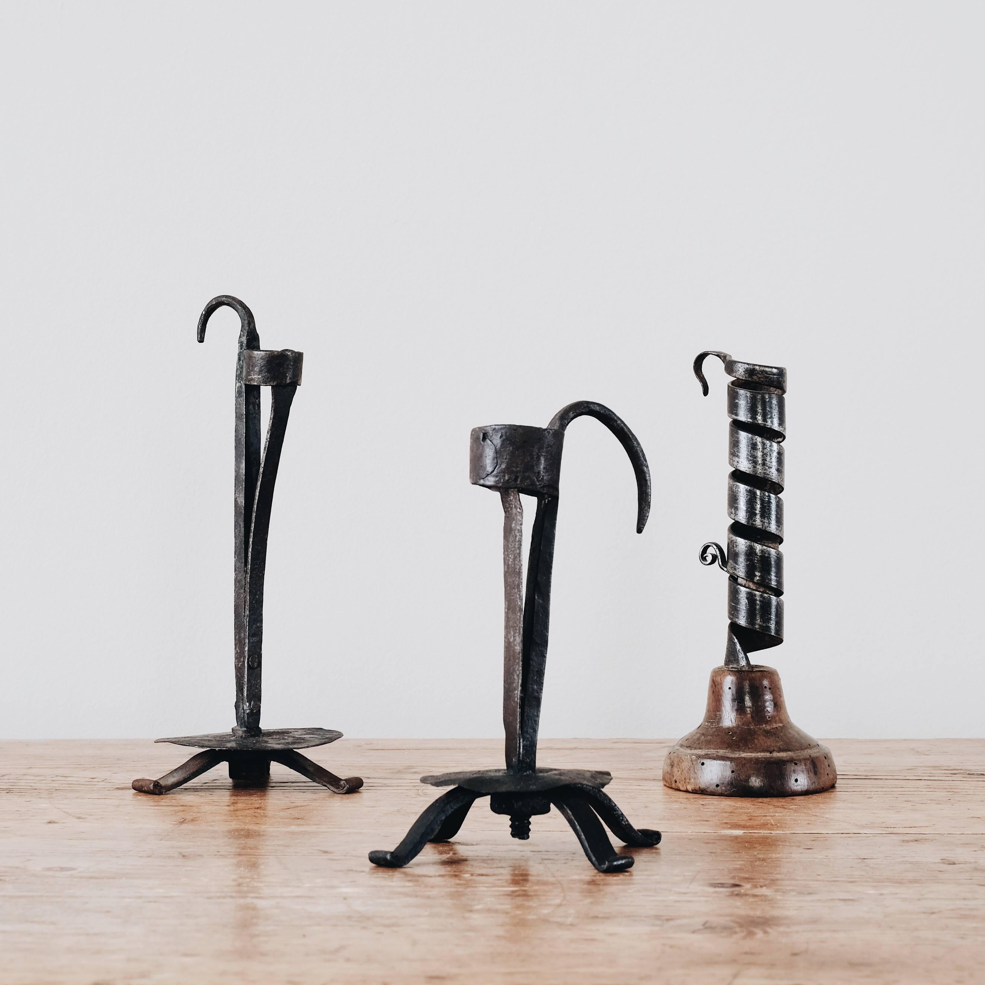 Great collection of two early 19th century Swedish wrought iron rush candleholders and one 18th century Swedish wrought iron spiral twist candleholder on a wooden base with an adjustable metal socket that holds the candle.