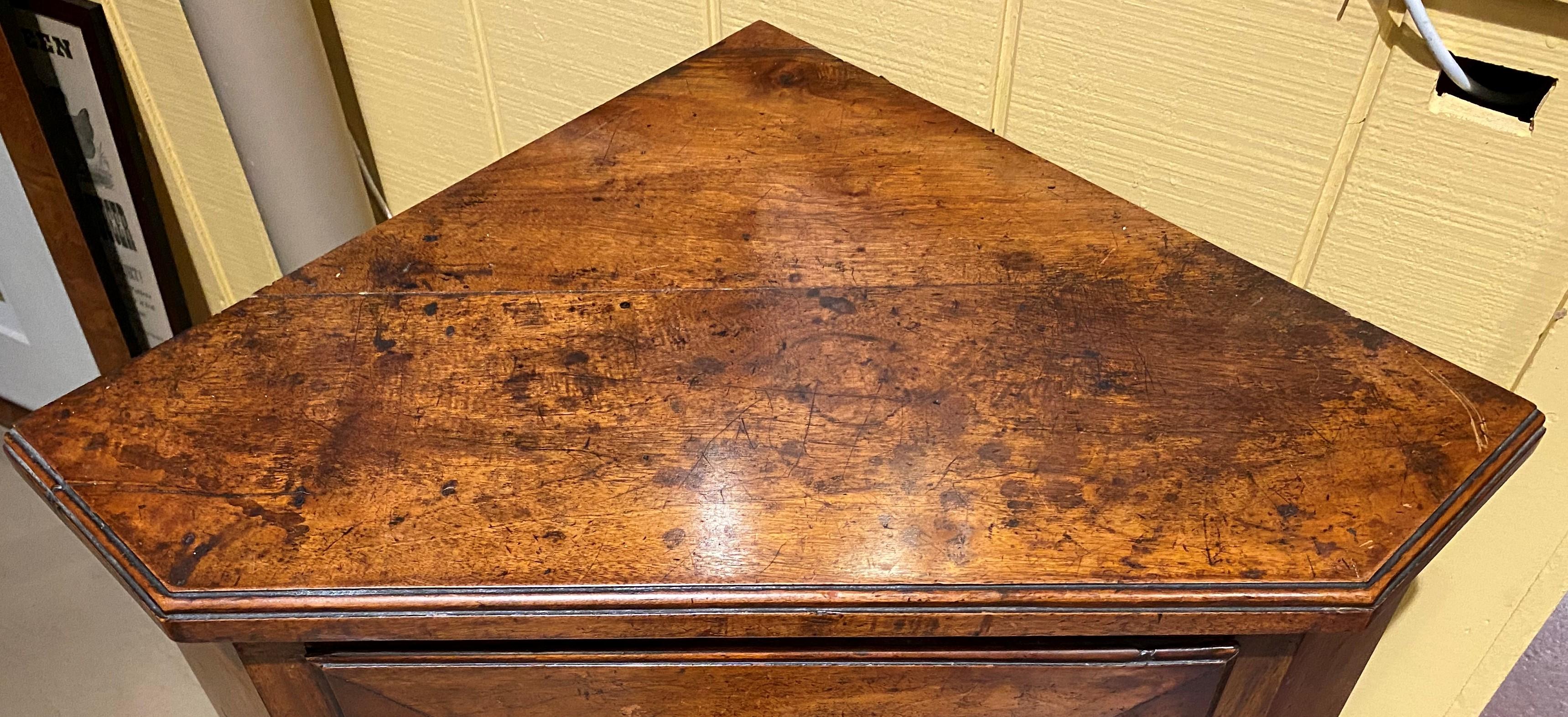 A fine rare mahogany standing corner cabinet  with molded edge top and a single paneled door, which opens to two interior storage shelves, and canted corners, all supported by three carved tapered legs. Probably English in origin, dating to the late