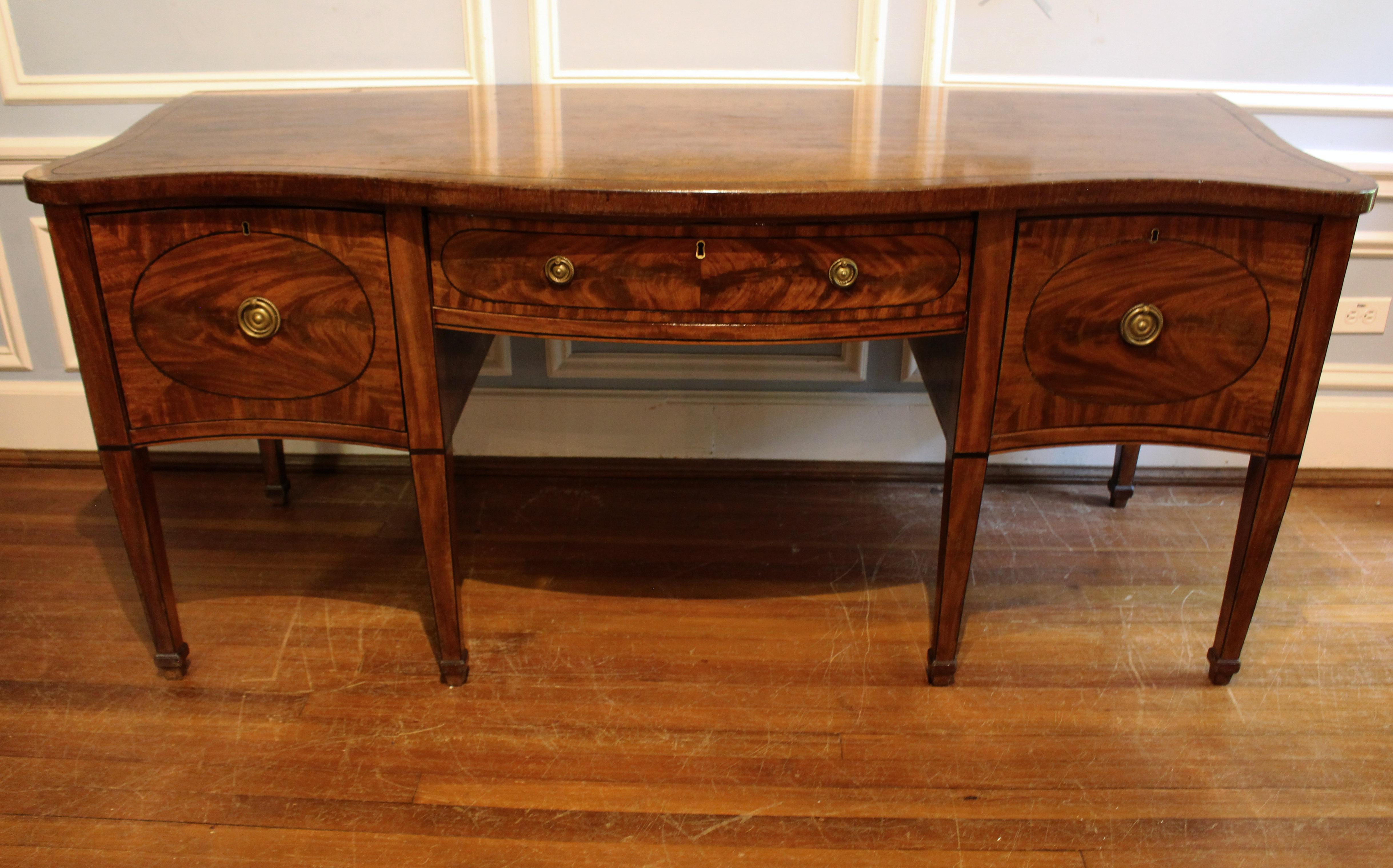Late 18th to early 19th century serpentine form sideboard, English, George III period. Mahogany with oak secondary wood. The figure of the mahogany put to excellent use particularly on the drawer fronts. Ebony line inlays outline & accent the whole.