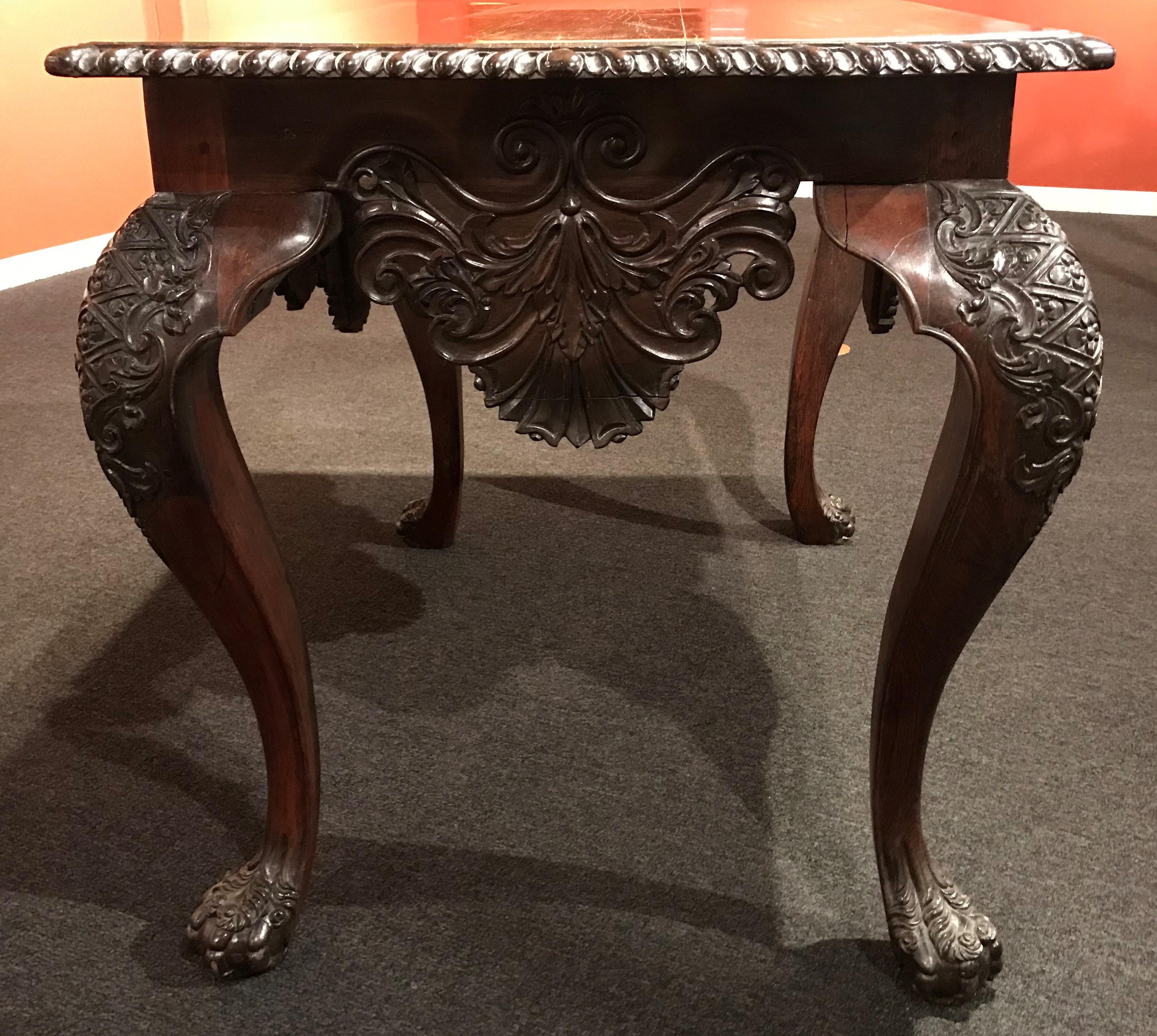 A rare exceptionally carved Rococo rosewood center table with rectangular top with gadrooned edge above a conforming frieze with an apron carved in deep relief with scrolling vinery centering a shell with a C-scroll molded frame, with the background