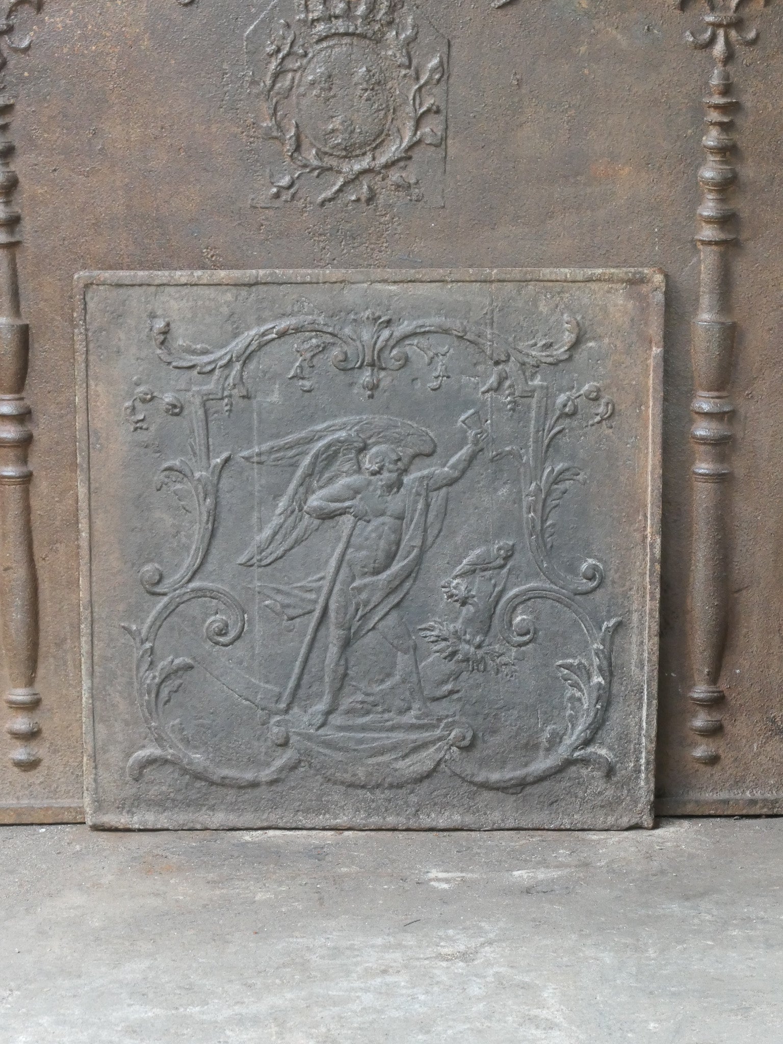 Late 18th or early 19th Century Neoclassical period French fire back with the time. The time, an old man with a scythe, symbol of the ephemeral character of life.

The fireback is made of cast iron and has a natural brown patina. Upon request it can