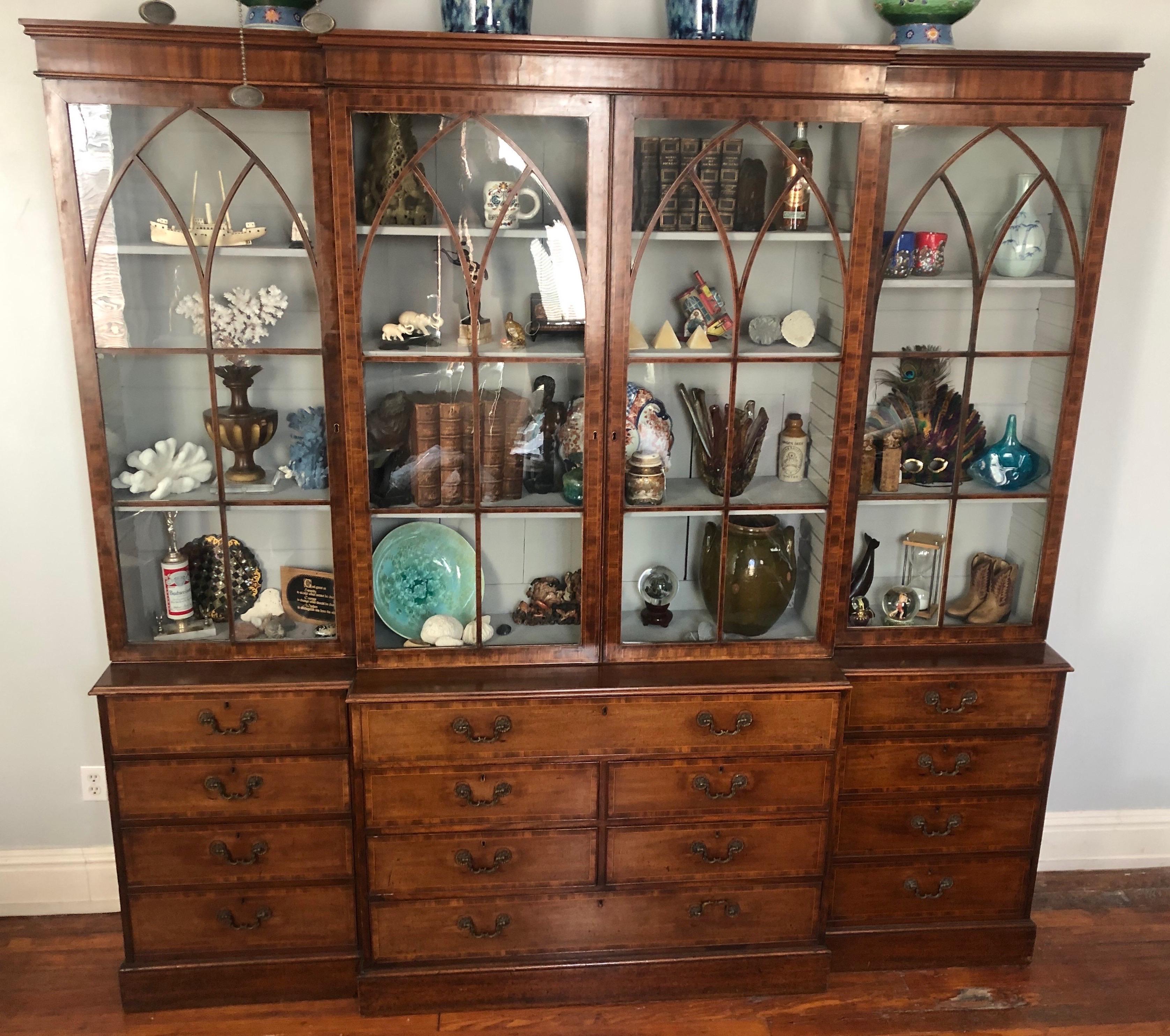 Fine period Georgian breakfront bookcase in mahogany with string inlay, crossbanding, and secretaries desk. 

Bookcase is made of 6 pieces. Top has crossbanded mahogany glazed doorswith a Gothic arch design. Bottom consists of 14 total drawers